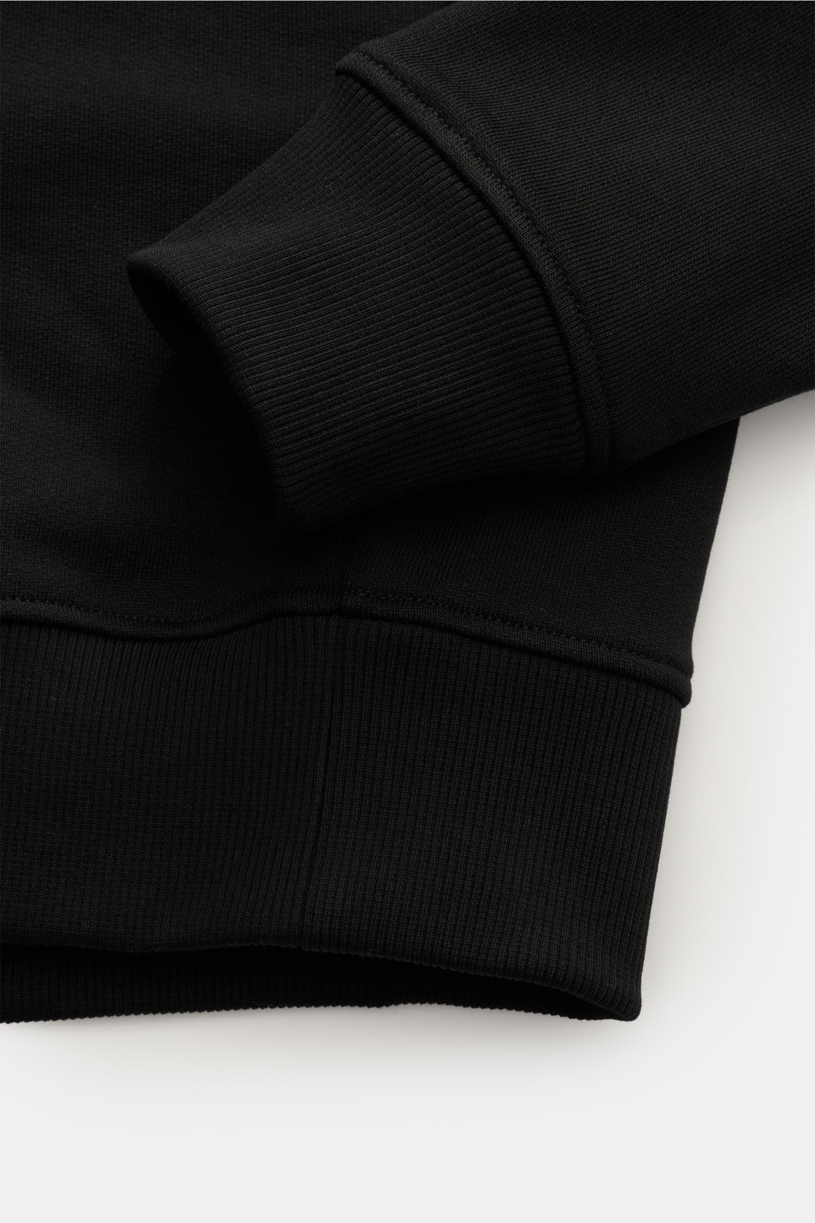 Close-up of the Ami Paris Rundhals-Sweatshirt schwarz showing ribbed cuffs and hem from a side angle; Love is in the air! Das markentypische Herz-Stitching auf der Brust wertet dieses Basic-Sweatshirt aus leicht stretchiger Bio-Baumwolle vom französisc