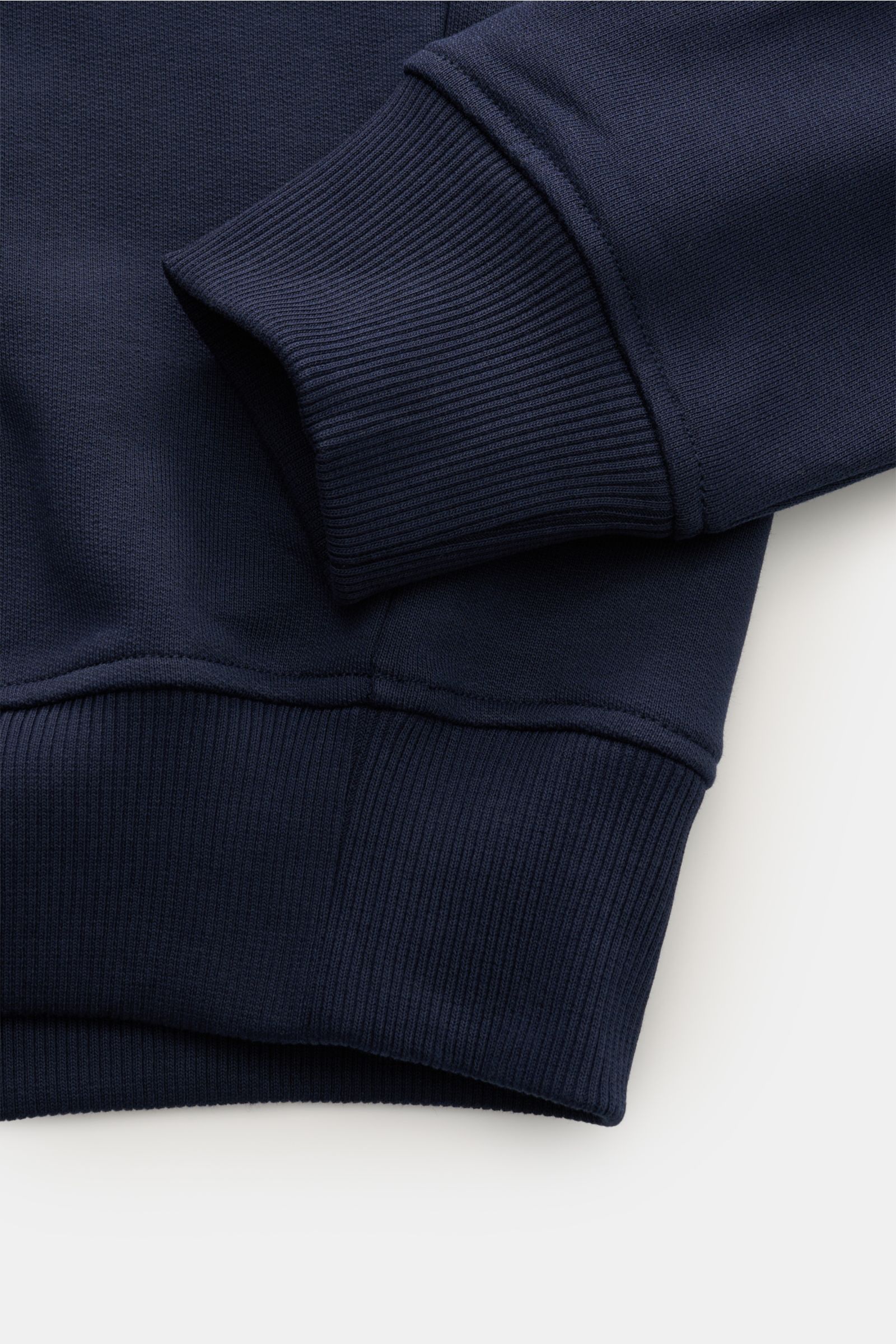 Close-up image of the cuff and bottom hem of the Ami Paris Rundhals-Sweatshirt dunkelblau, photographed from above, showing dark blue ribbed cuffs and hem. Love is in the air! Das markentypische Herz-Stitching auf der Brust wertet dieses Basic-Sweatshirt 