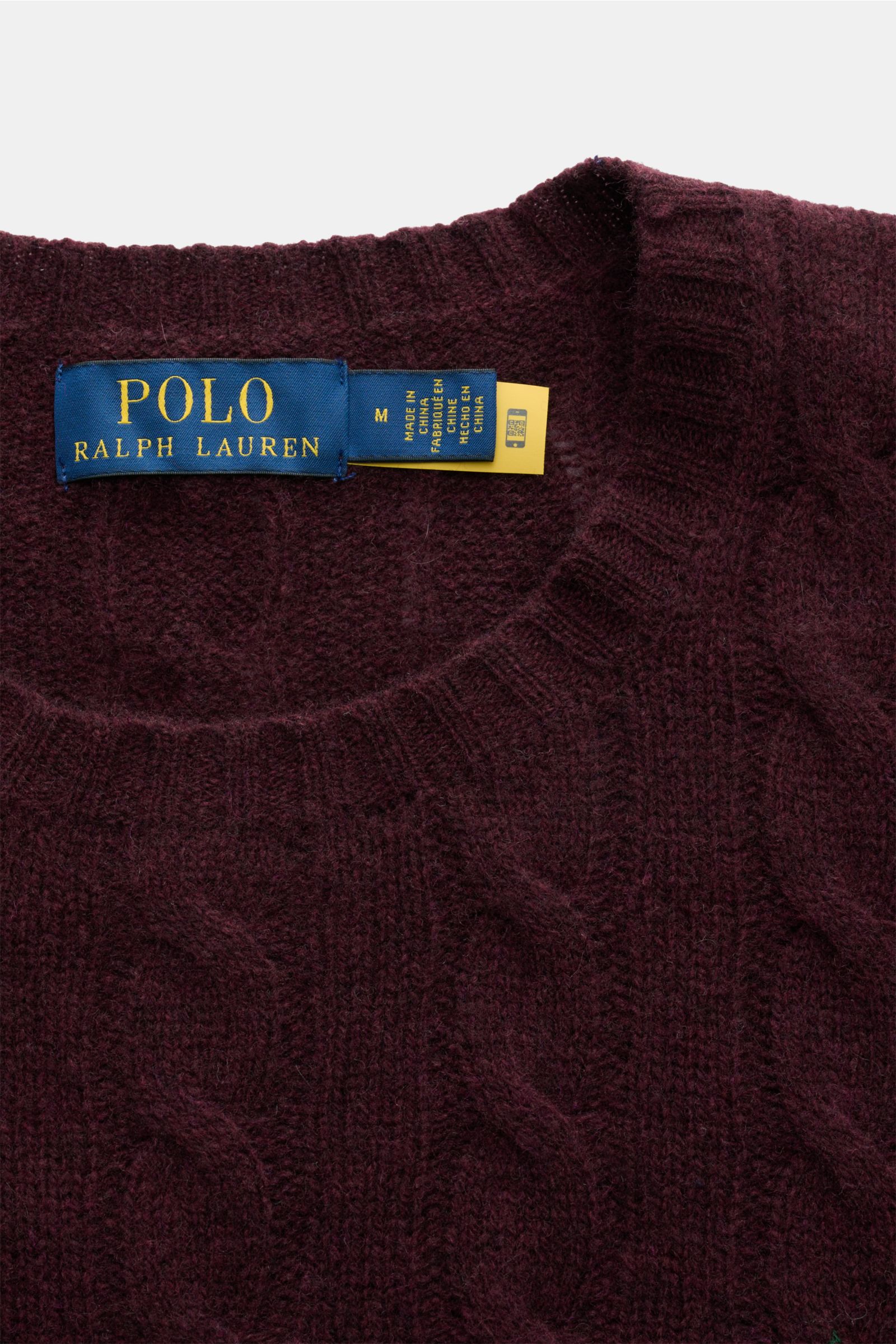 Close-up from above of the Polo Ralph Lauren Rundhalspullover bordeaux showing the textured cable knit wool-cashmere blend, round neckline, and brand label with Polo player stitching and comfortable ribbed cuffs. This classic features a slim fit and fine 