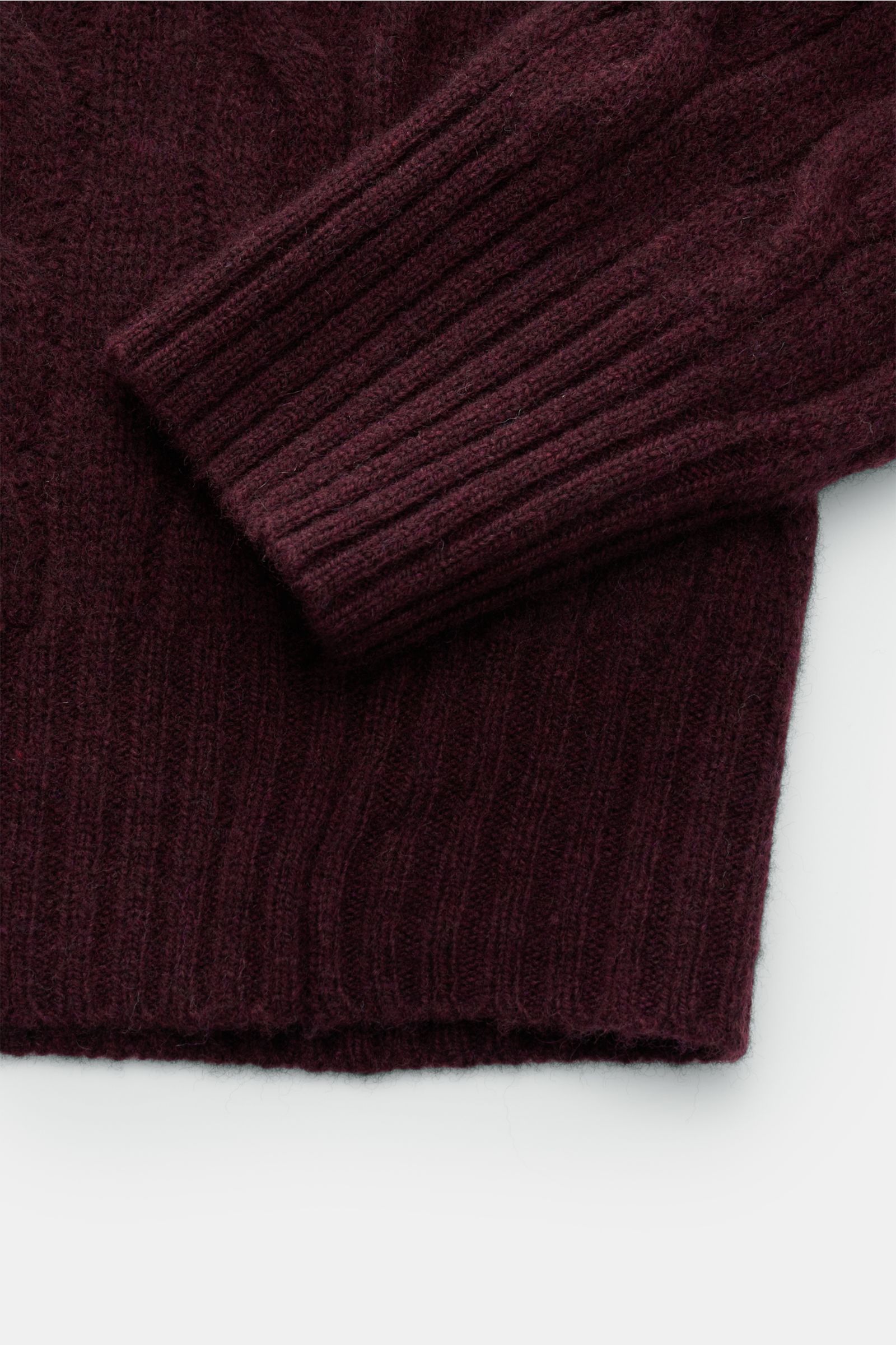 Close-up image of the sleeve and hem of the Polo Ralph Lauren Rundhalspullover bordeaux, photographed from above, showing its soft wool and cashmere mix with a fine, structured cable knit pattern, slim fit, ribbed cuffs, and characteristic polospieler-sti