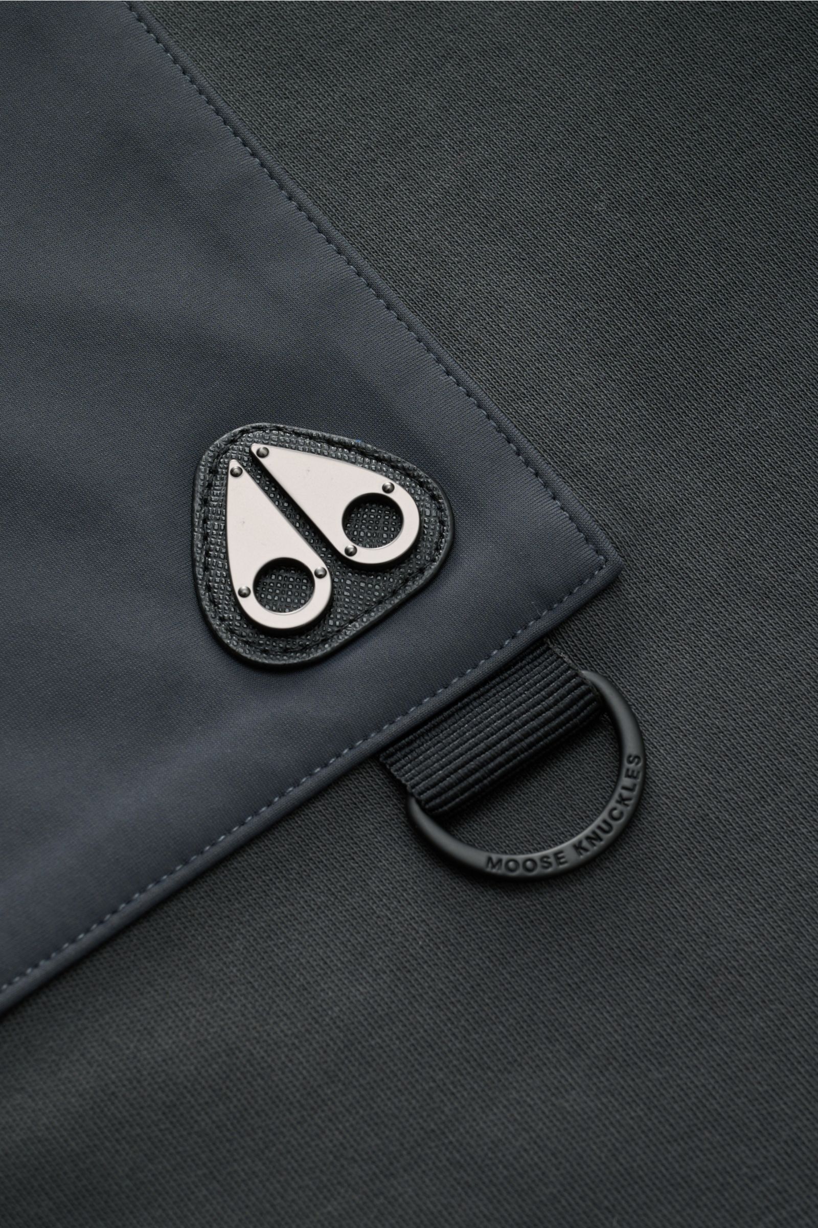 Nahaufnahme des Moose Knuckles Rundhals-Sweatshirts 'Dalon Crew' dunkelgrau, vorn Zipper-Tasche mit Metall-Logo, glatter Baumwoll-Jersey, breite Bündchen.