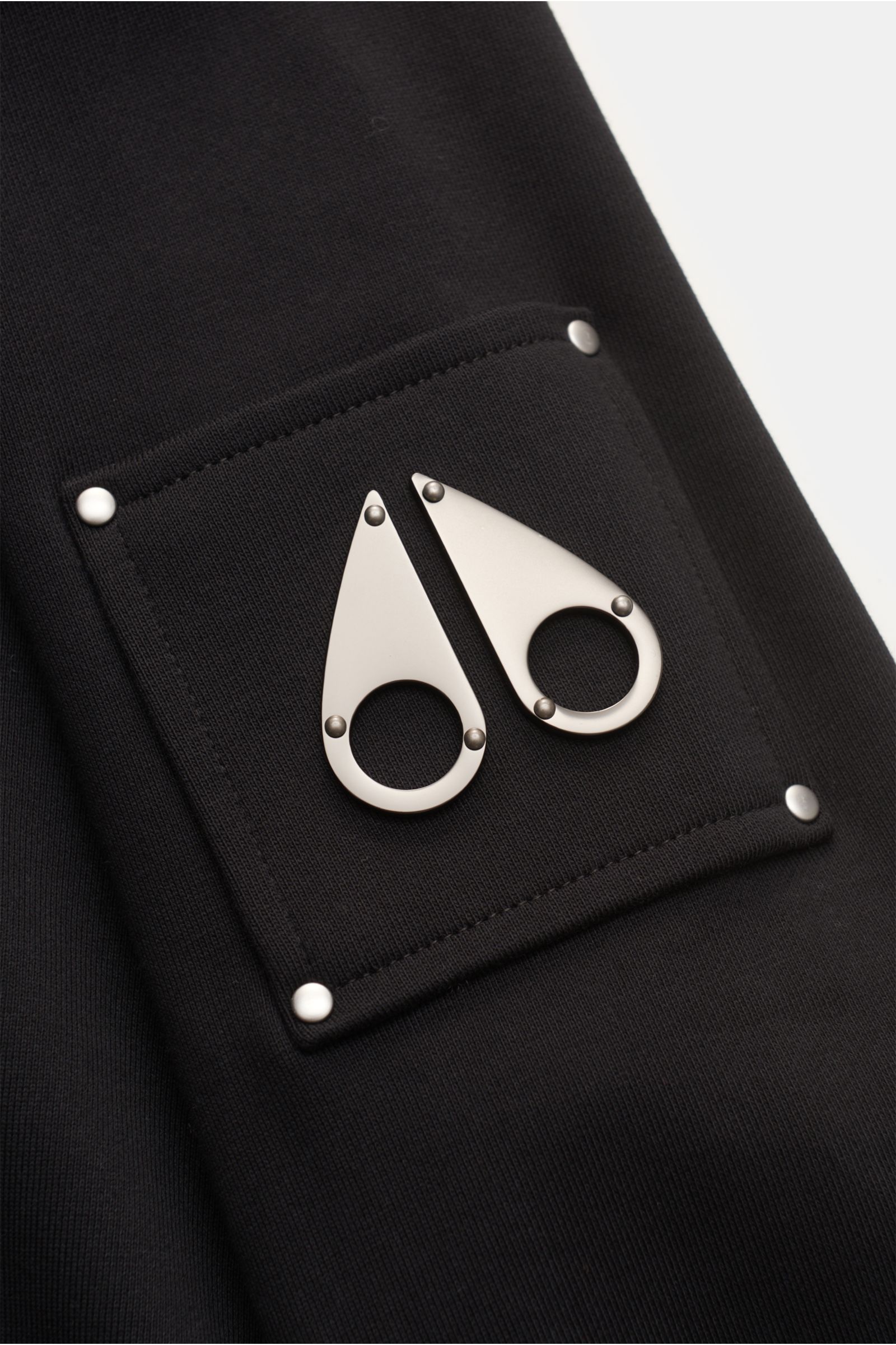 Moose Knuckles Sweatshirt 'Hartsfield Crew' schwarz, Detailaufnahme des Oberarm-Patches mit Metall-Logo, reine Baumwolle, weicher Griff, Regular Fit.