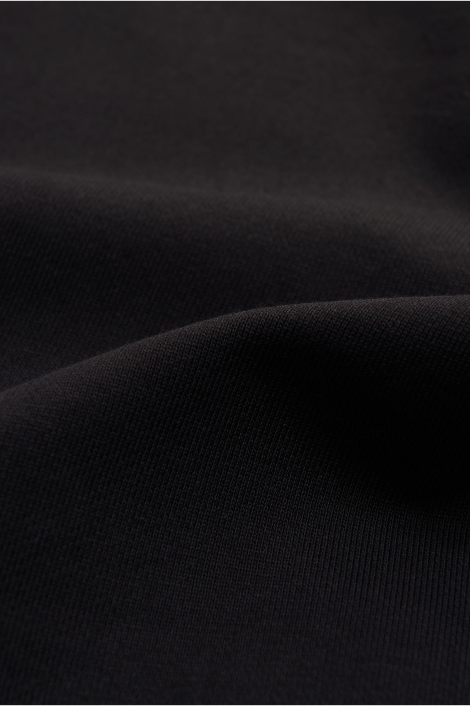 Moose Knuckles Sweatshirt 'Hartsfield Crew' schwarz, Detailaufnahme des weichen Baumwollstoffs mit Metall-Logo-Patch am Oberarm, von nah fotografiert.