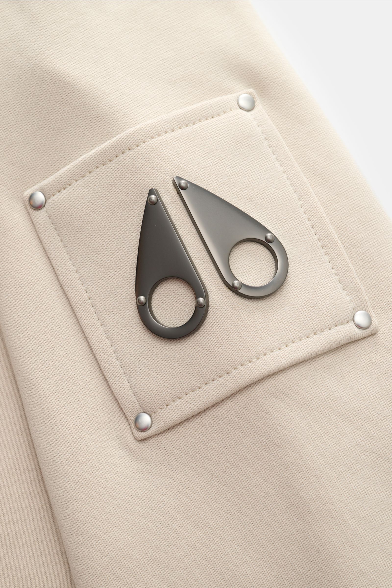 Moose Knuckles Sweatshirt 'Hartsfield Crew' creme Detailaufnahme des Oberarm-Patches mit Metall-Logo aus reiner Baumwolle, weicher Griff.