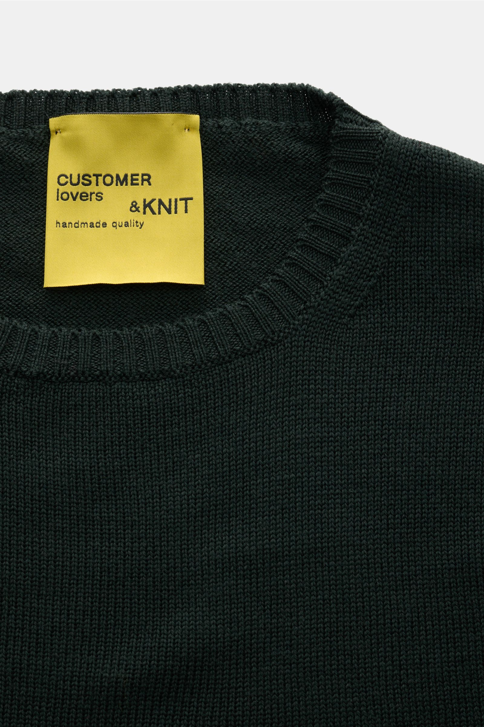 B.F. Knitwear Merino Rundhalspullover dunkelgrün aus reine Merinowolle, weicher Griff, mittelgrobes Strickbild, Slim Fit, Rundhalsausschnitt, flexible Rippstrick-Bündchen, Nahaufnahme von oben.