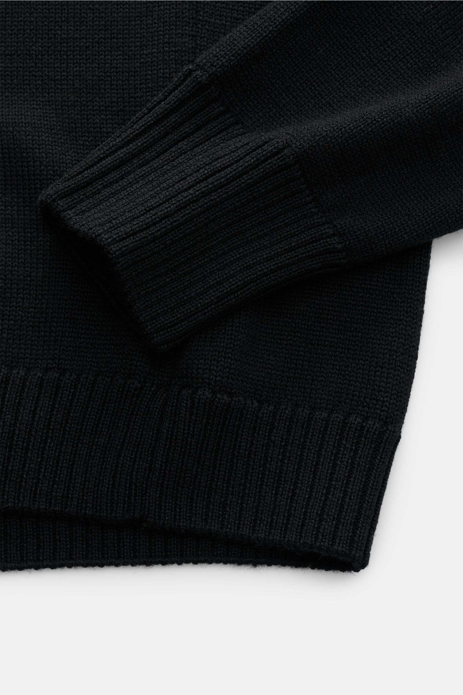 B.F. Knitwear Merino Rundhalspullover schwarz, Detailaufnahme von Ärmel und Saum, reine Merinowolle, weicher Griff, mittelgrobes Strickbild, Slim Fit, Rundhalsausschnitt, flexible Rippstrick-Bündchen.