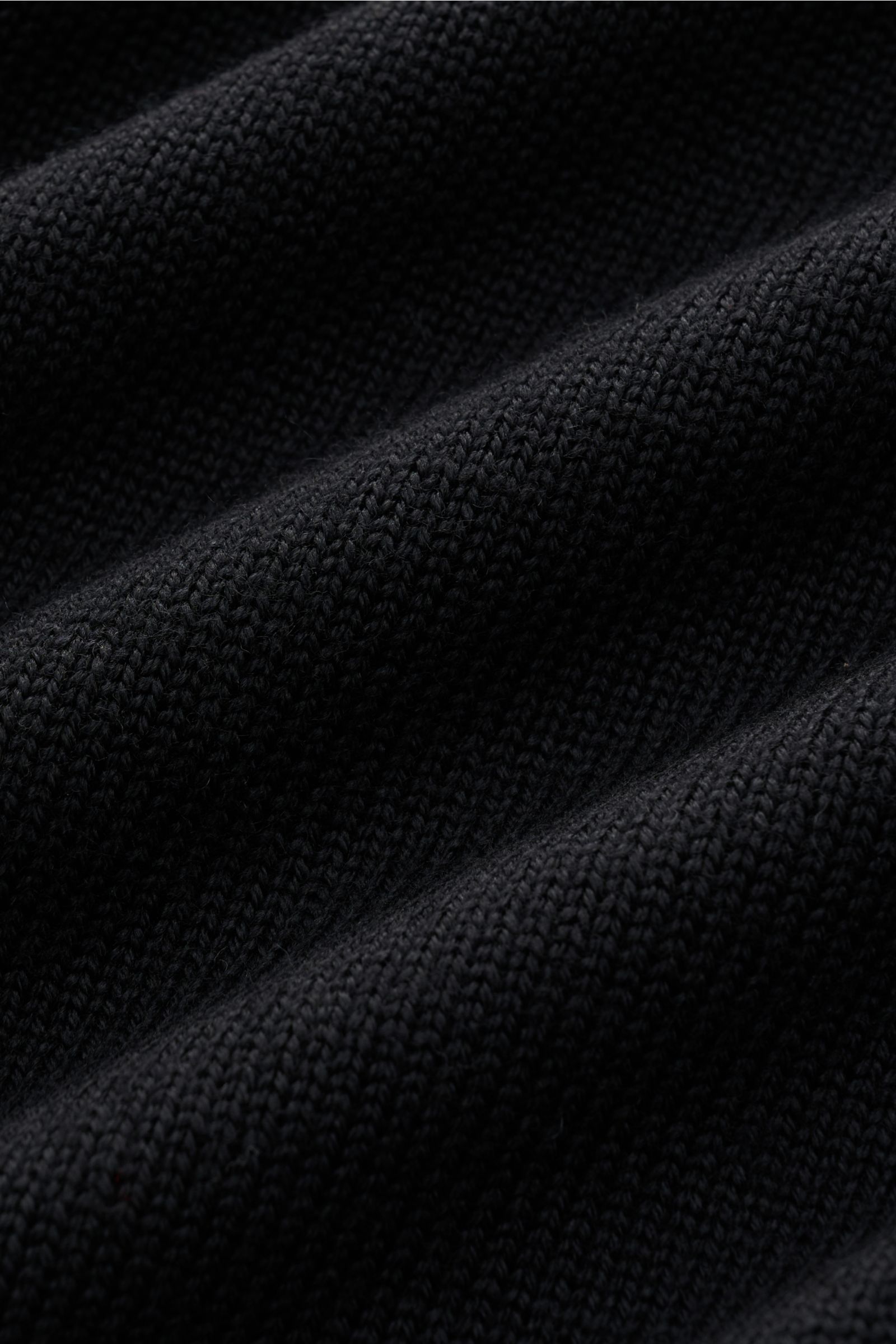 Nahaufnahme des mittelgroben Strickbilds vom schwarzen B.F. Knitwear Merino Rundhalspullover, reine Merinowolle, weicher Griff, Slim Fit, Rundhalsausschnitt, flexible Rippstrick-Bündchen.