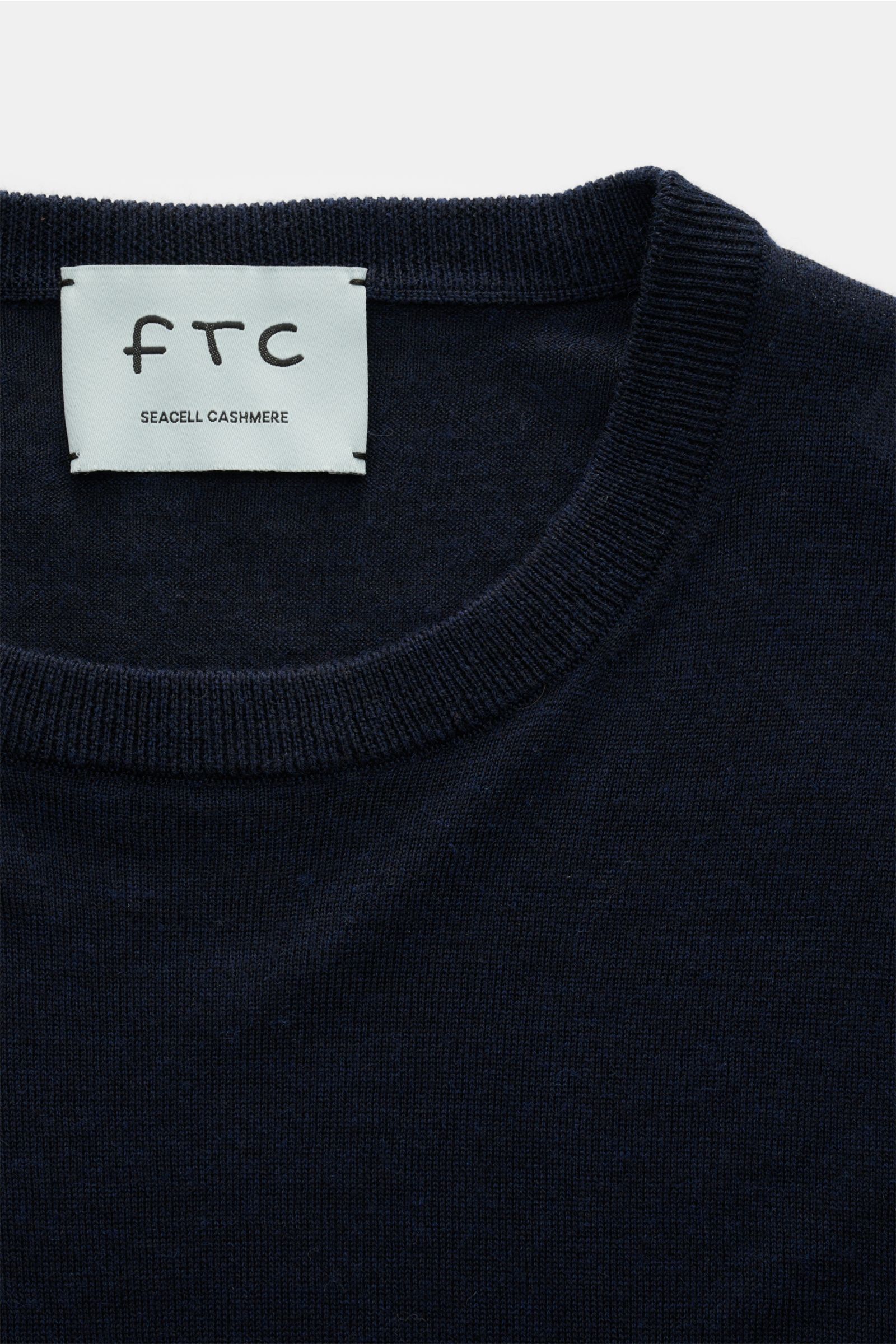 Nahaufnahme von Rundhalsausschnitt und Label des FTC Feinstrick-Rundhalspullover navy aus Cashmere-Lyocell-Mix, Slim Fit, OEKO-TEX® zertifiziert, weicher Griff, feines Strickbild, Rippbündchen.