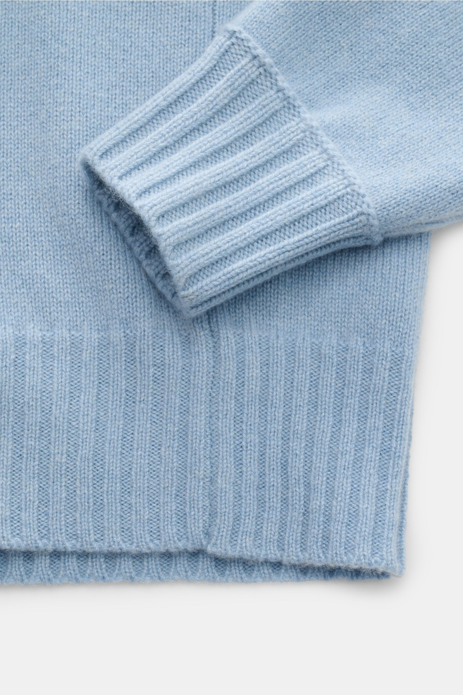 Close-up image of the FTC Cashmere crew neck jumper light blue, showing the sleeve and lower hem from a top-down perspective. Pure fair trade cashmere, OEKO-TEX® certified, very soft feel, medium-fine knit, slim fit, crew neck, raglan sleeves, comfortable