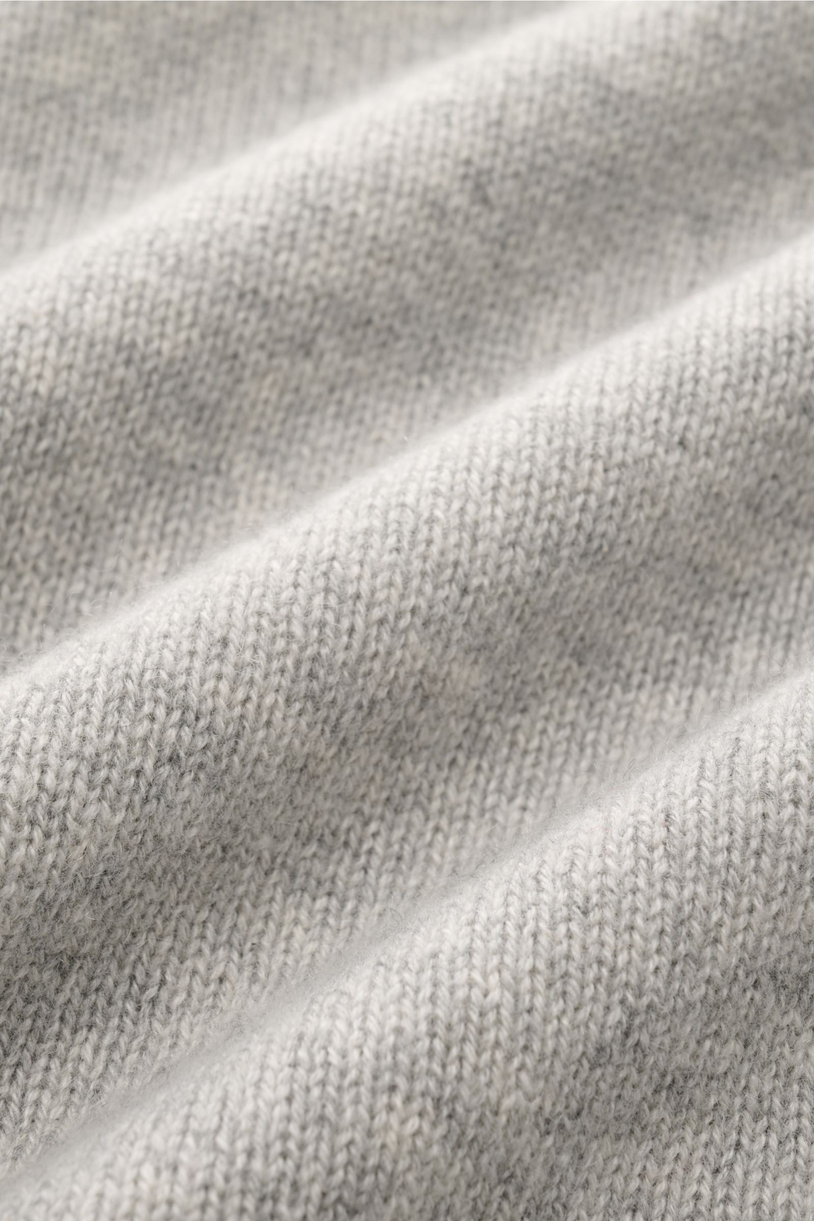 Close-up image of the FTC Cashmere crew neck jumper grey mottled fabric, showing medium-fine knit texture from a detailed front perspective. Pure fair trade cashmere, OEKO-TEX® certified, very soft feel, slim fit, crew neck, raglan sleeves, and comfortabl