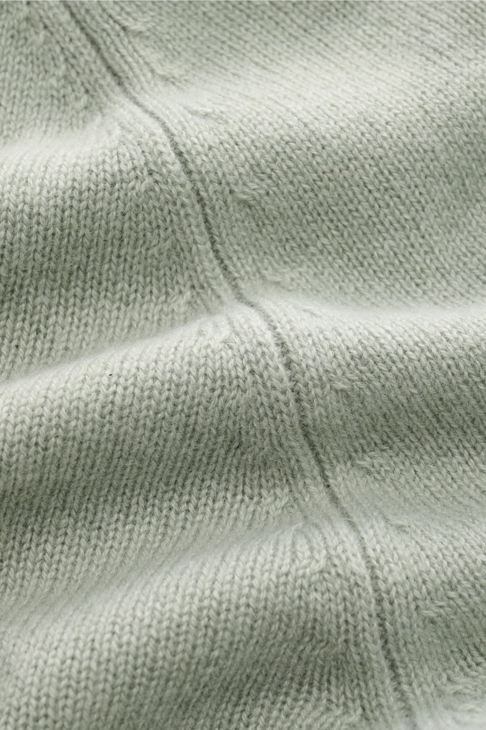 Nahaufnahme des graugrünen FTC Cashmere Rundhalspullovers mit mittelfeinem Strickbild, Reißverschlussnaht, reiner Fair-Trade-Cashmere, OEKO-TEX® zertifiziert, sehr weicher Griff, Slim Fit, Rundhalsausschnitt, Raglanärmel und komfortablen Rippbündchen.