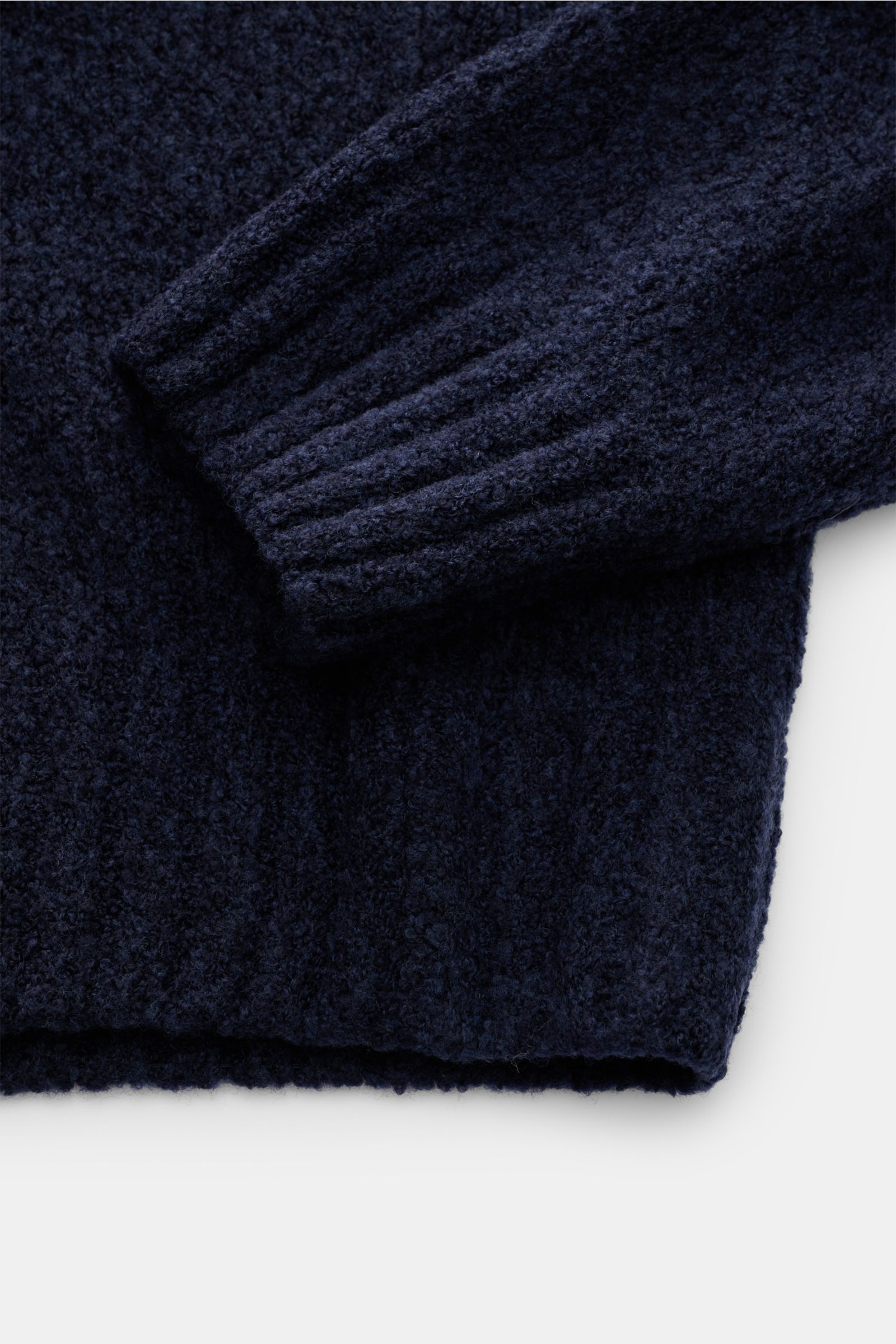 Close-up top-down view of the navy 04651/ A trip in a bag Rundhalspullover 'Grainy Crew' showing its soft bouclé texture, slim fit, round neckline, and flexible ribbed cuffs. Inspiriert von den Kontrasten Finnlands – wo zeitloses Design und Naturverbunden