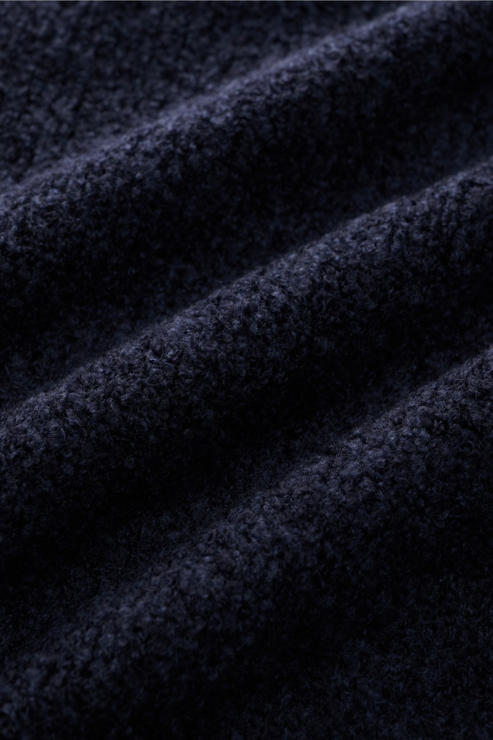 Close-up fabric texture of the 04651/ A trip in a bag Rundhalspullover 'Grainy Crew' navy, photographed from a top angle showing the soft bouclé wool and microfiber blend with a slim fit and round neckline. Inspiriert von den Kontrasten Finnlands – wo zei