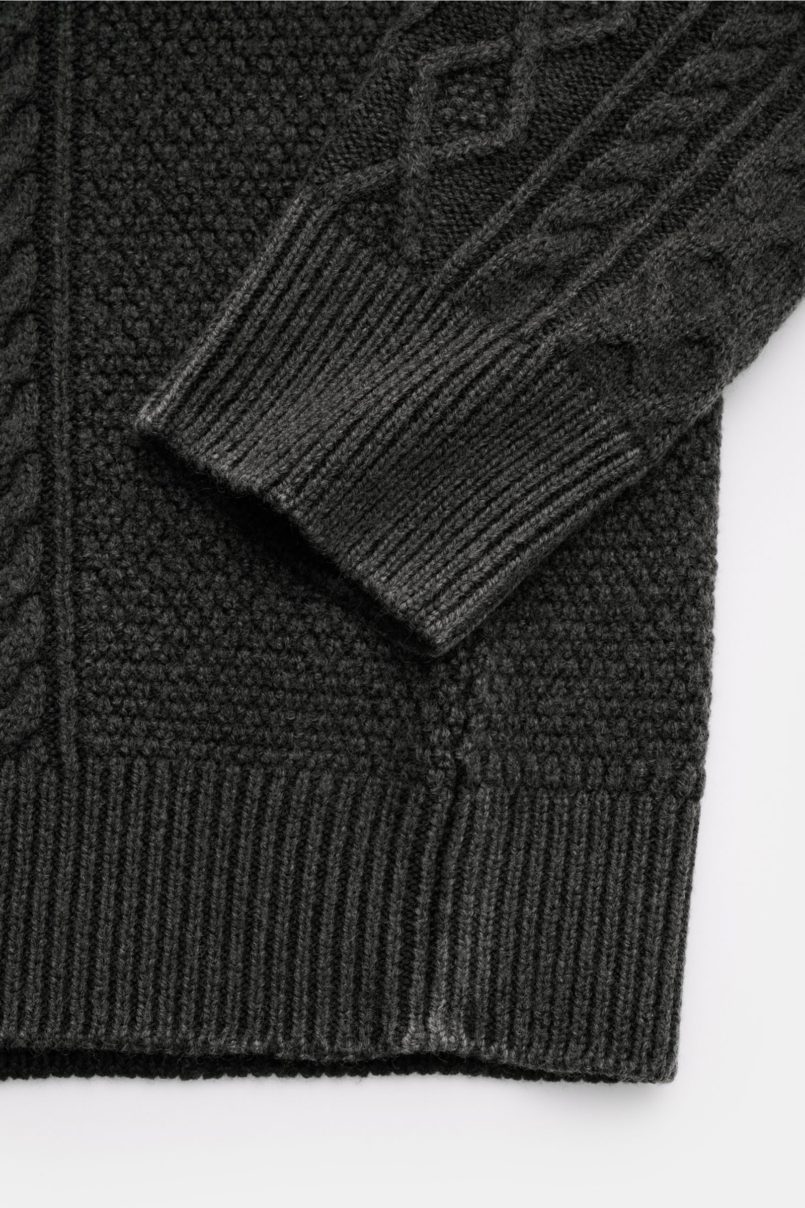 Close-up of the sleeve and hem of the 04651/ A trip in a bag Rundhalspullover 'Foggy Cable Crew' dunkelgrau, showing classic cable knit patterns and ribbed cuffs in soft pure wool from a top-down perspective, featuring a garment-dye design for a natural v