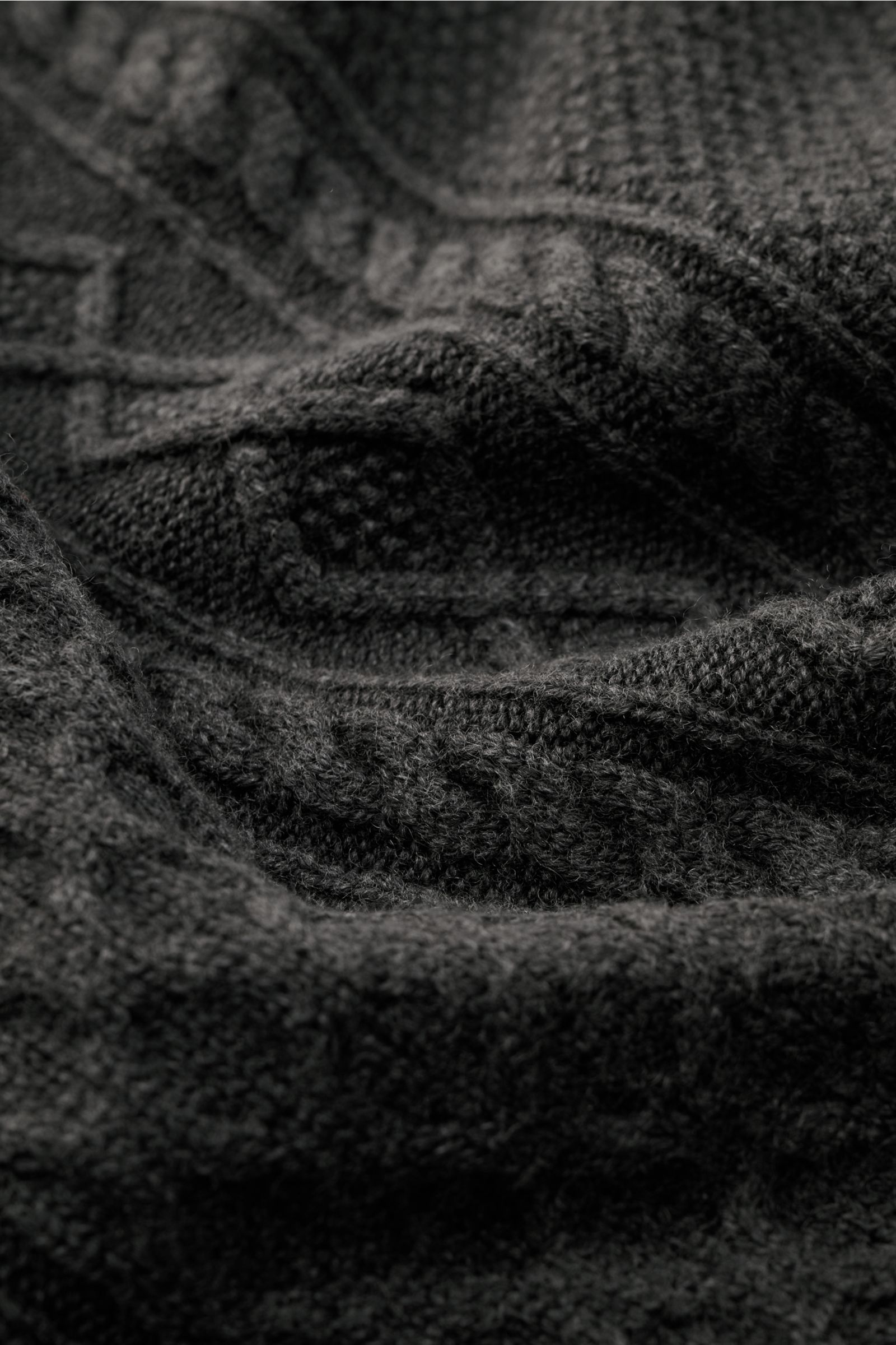 Close-up view of the 04651/ A trip in a bag Rundhalspullover 'Foggy Cable Crew' dunkelgrau, showing classic cable knit, soft pure wool, garment-dye vintage look, round neckline, ribbed cuffs, and voluminous texture.