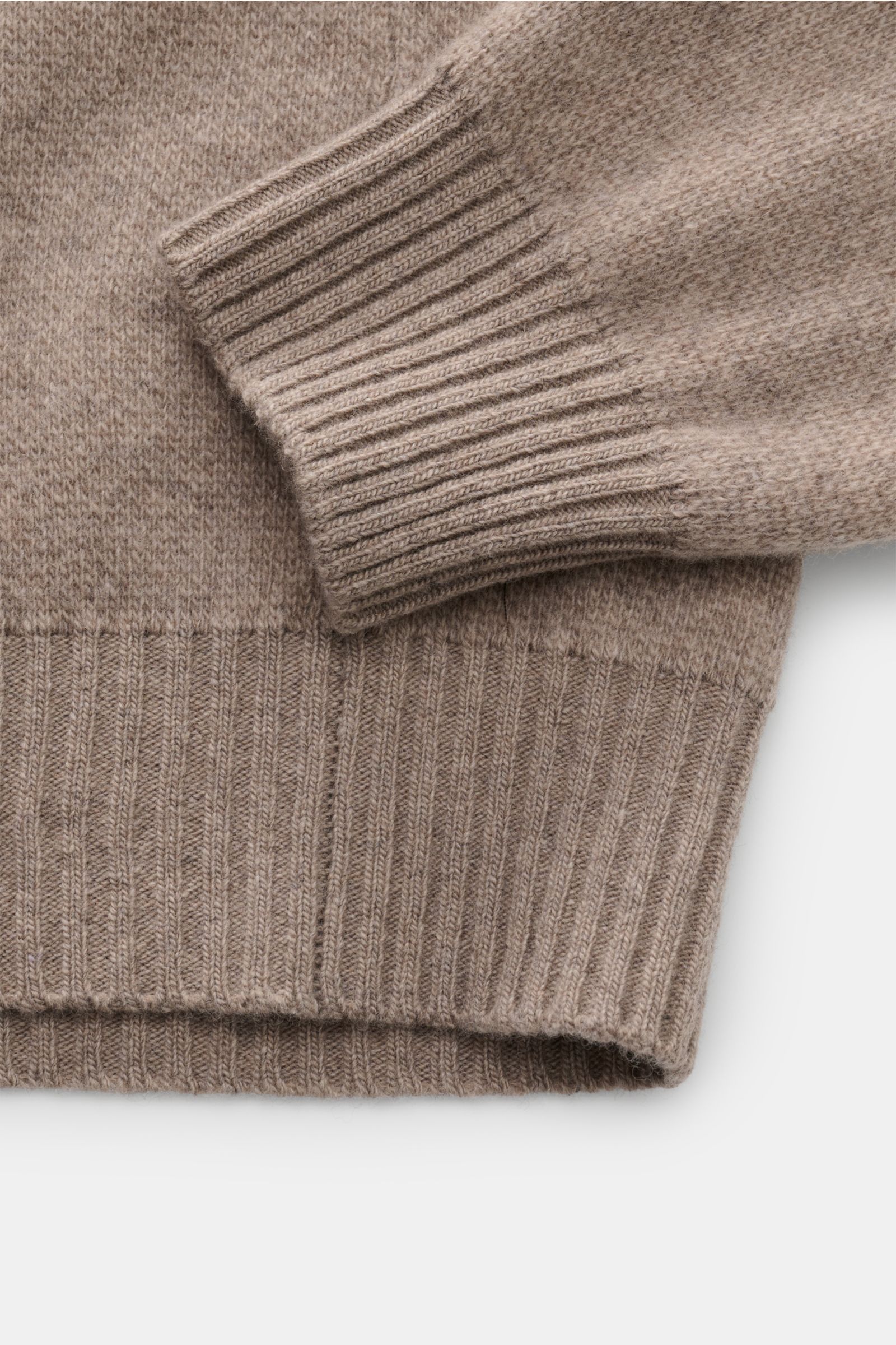 Nahaufnahme des Ärmels und Bundes des 04651/ A trip in a bag Rundhalspullover 'Landscape Crew' taupe/beige/hellblau meliert aus Wolle-Cashmere-Mix mit Rippenbündchen, mittelfeinem Strickbild und Jacquard-Landschafts-Design, fotografiert von oben.