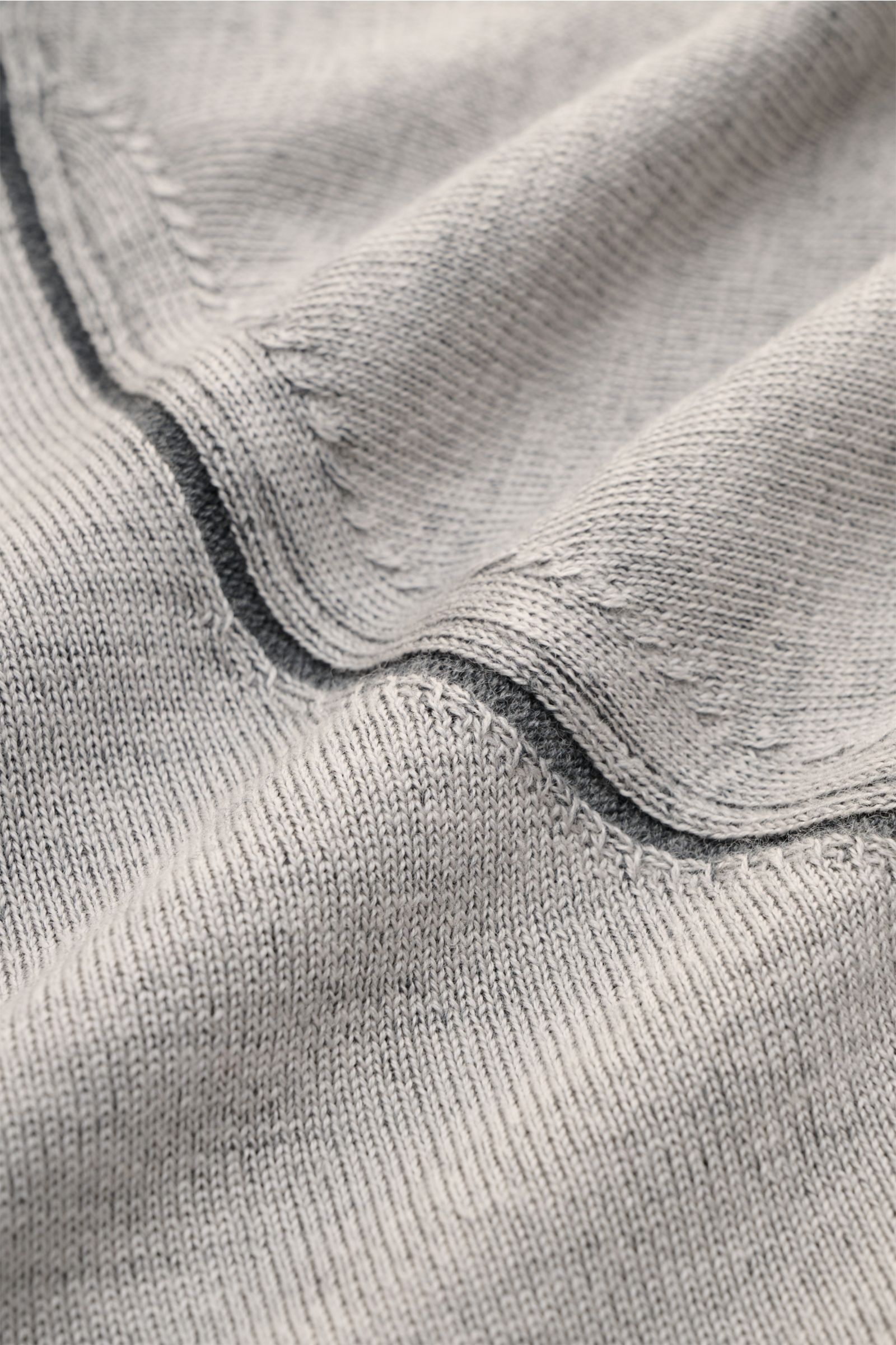Close-up view of the Kiefermann Merino Rundhalspullover 'Lutzs' hellgrau meliert showing soft, fine-knit light grey merino wool with contrasting inner details and rolled neckline edges.

Update für ein Essential: Der Rundhalspullover von KIEFERMANN aus
