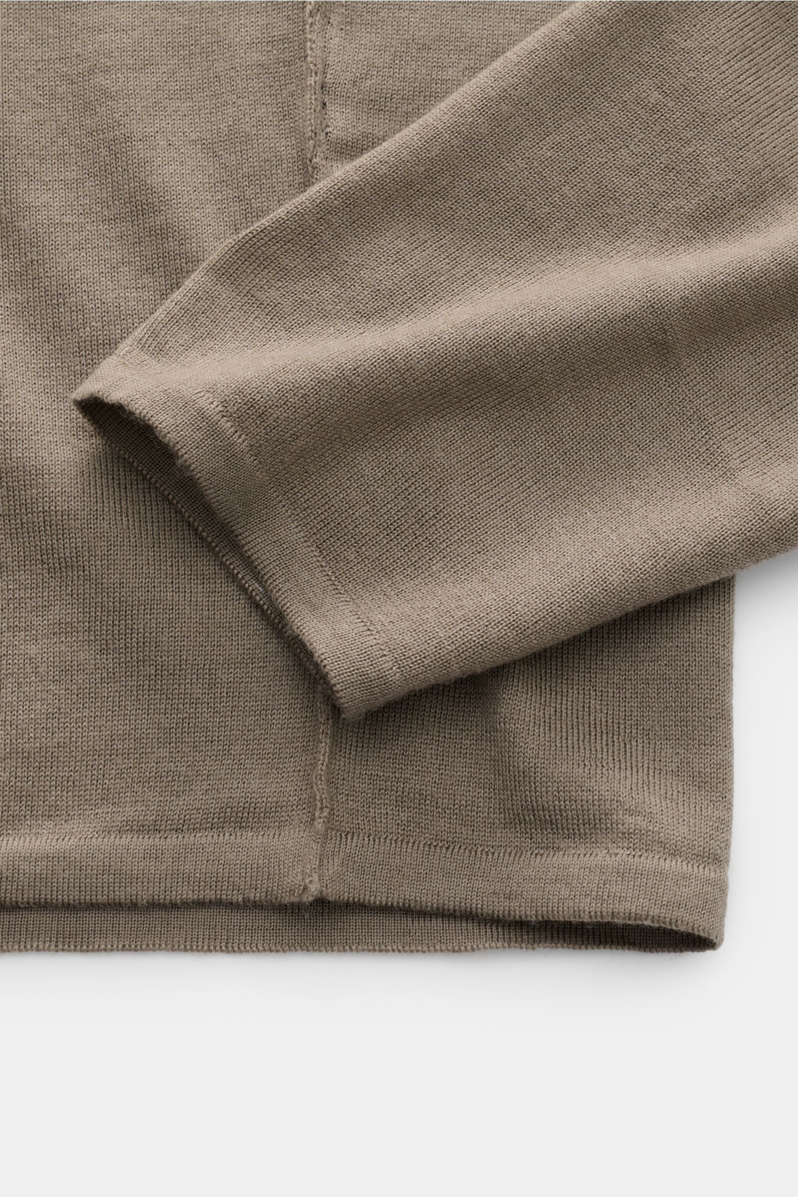 Close-up photo from above of the sleeve and hem of the Kiefermann Merino Feinstrick-Pullover 'Marleys' taupe showing fine knit texture, slim fit, and elastic hems, made of reine Merinowolle with supersofter Griff, sehr feines Strickbild, klassischer Rundh