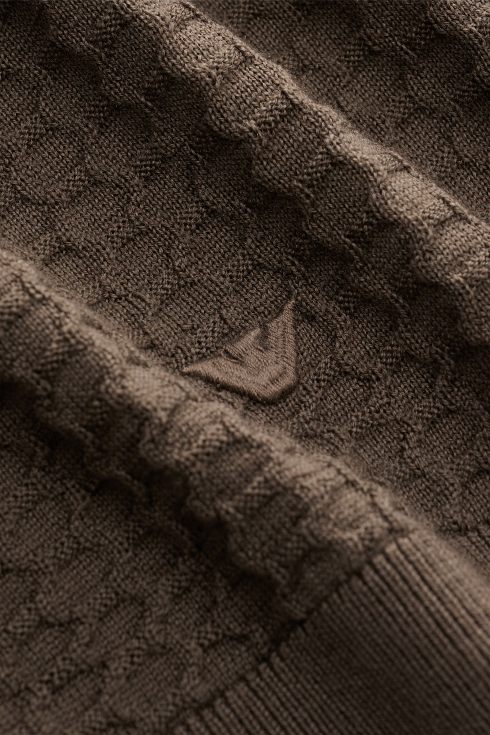 Nahaufnahme des Emporio Armani Rundhalspullover graubraun mit feinem Strukturstrick, weichem Griff und Weblabel am Saum.