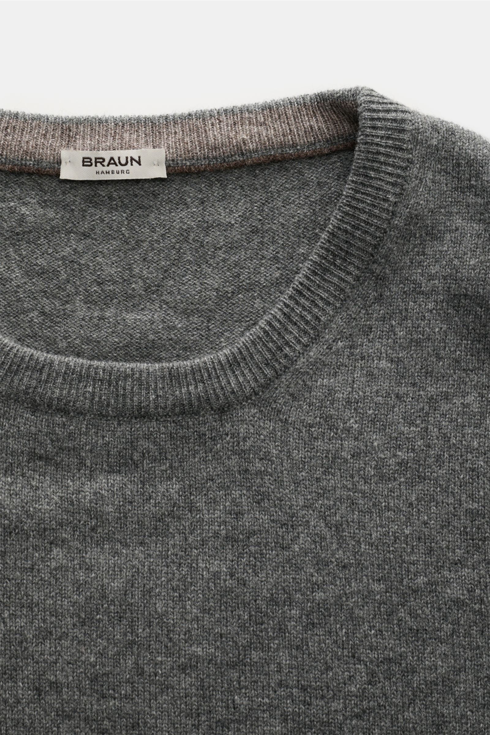 Close-up front view of the von Braun Rundhals-Pullover anthrazit showing soft, fine knit fabric with ribbed round neckline and label. Ein komfortables Basic für vielseitige Looks: Der softe VON BRAUN Pullover aus edlem Materialmix mit Wolle, Viskose und C