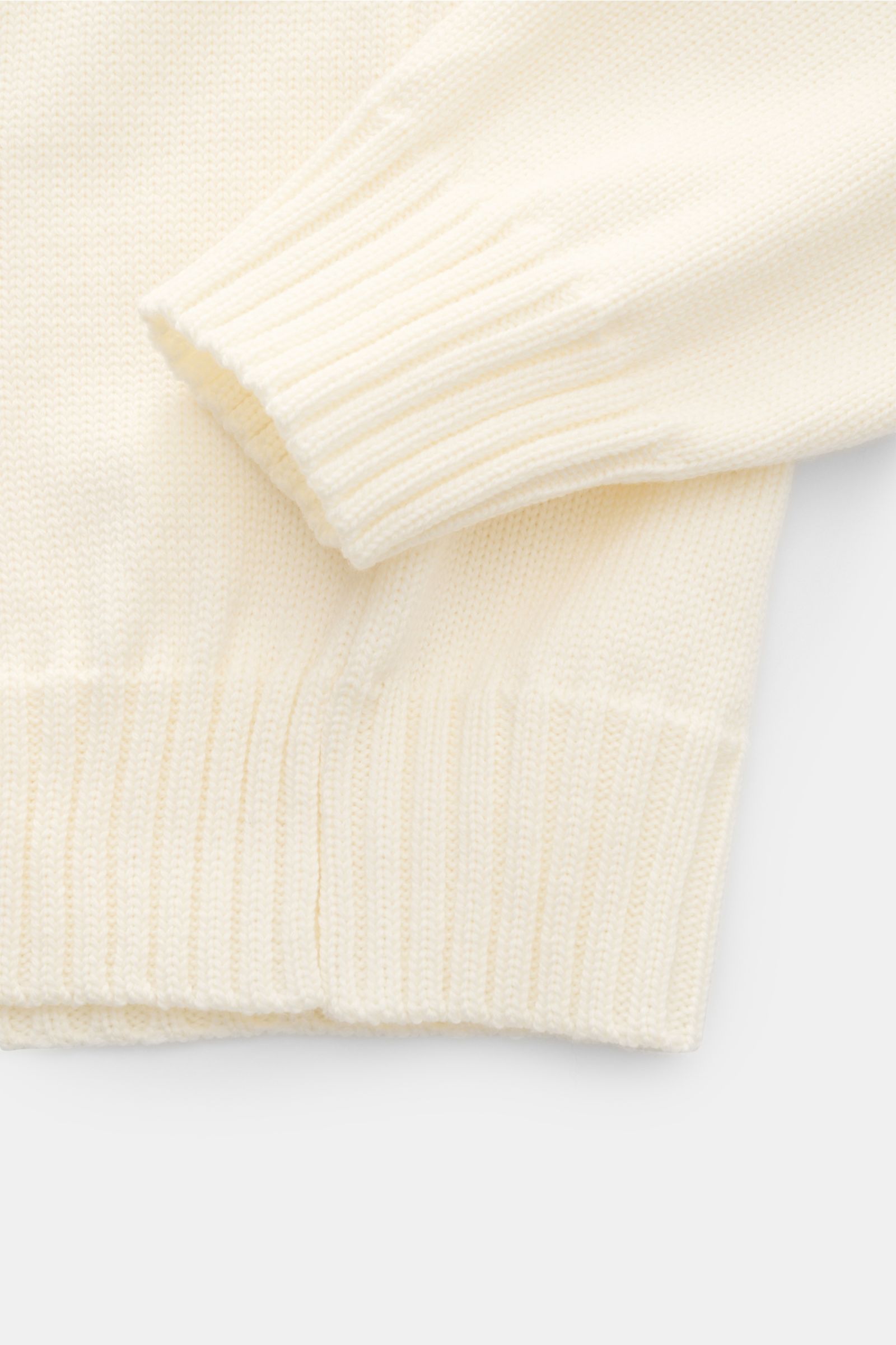 Ace Denim Merino Rundhalspullover creme, Detailaufnahme von Ärmel und Bund mit weichem, mittelgrobem Strick und breiten Rippbündchen aus reiner Merinowolle.