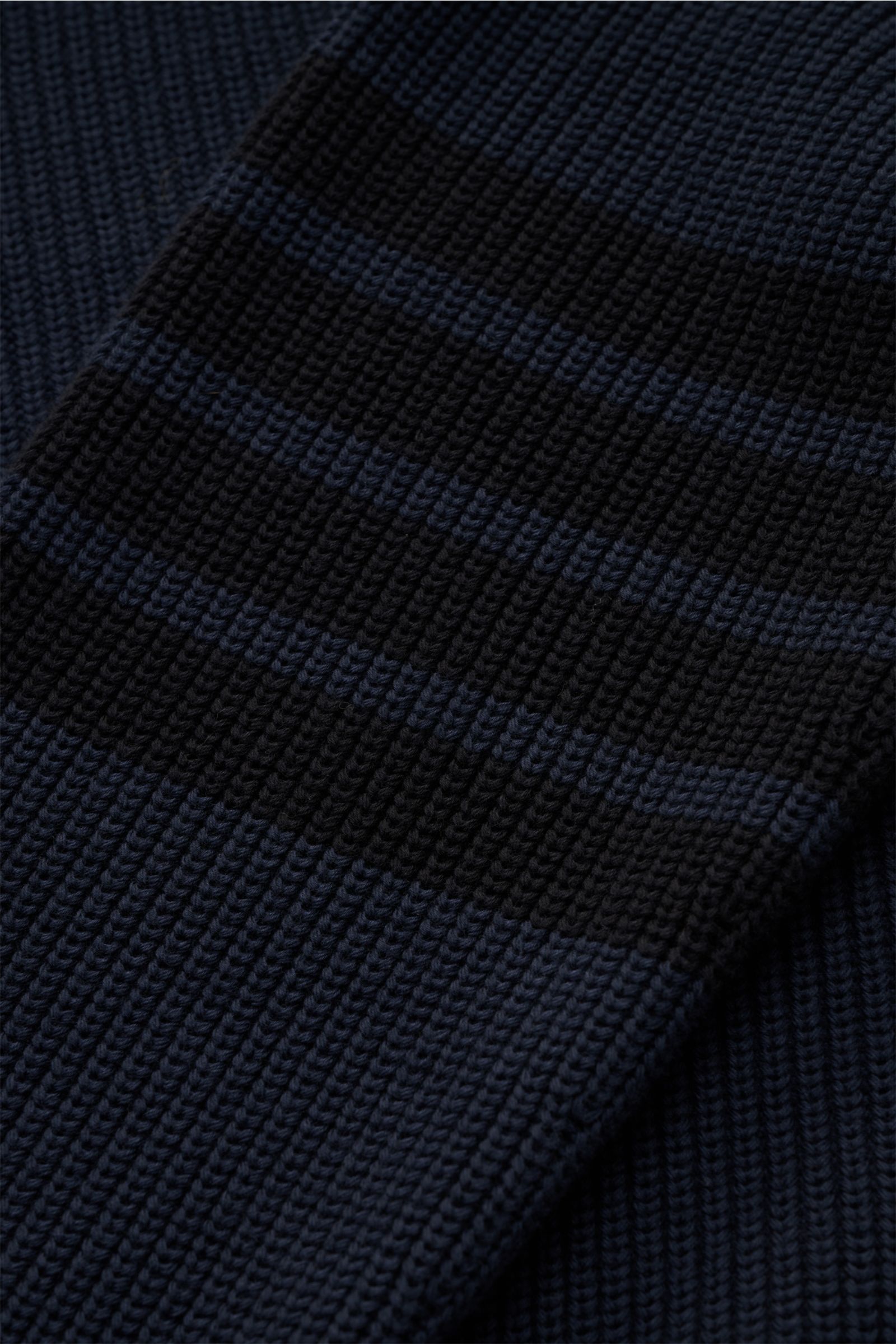Close-up image of the Thom Browne Rundhalspullover graublau sleeve, showing a soft, pure cotton knit with tonal stripes, buttoned cuffs, and a medium ribbed texture, photographed from a top-down angle. Stilvoll durch die kalte Saison: Der Rundhalspullover