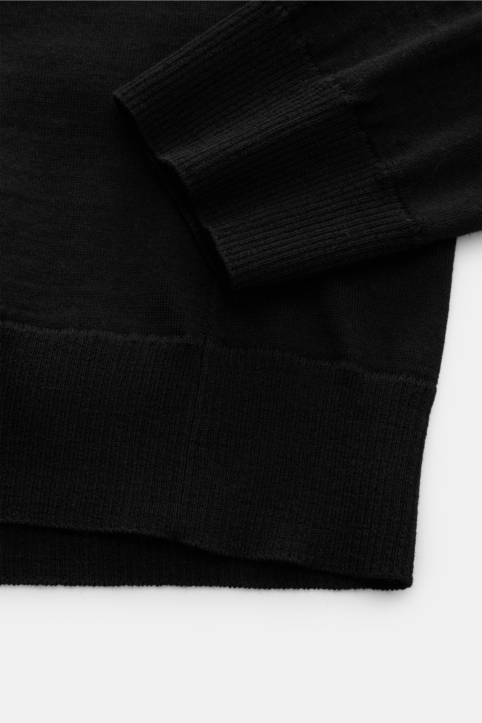 Stone Island Rundhalspullover 'Ghost Piece' schwarz, Slim Fit, aus reiner Wolle mit feinem Strickbild, Rippbündchen, Kompass-Badge, Detailaufnahme Ärmel und Saum.