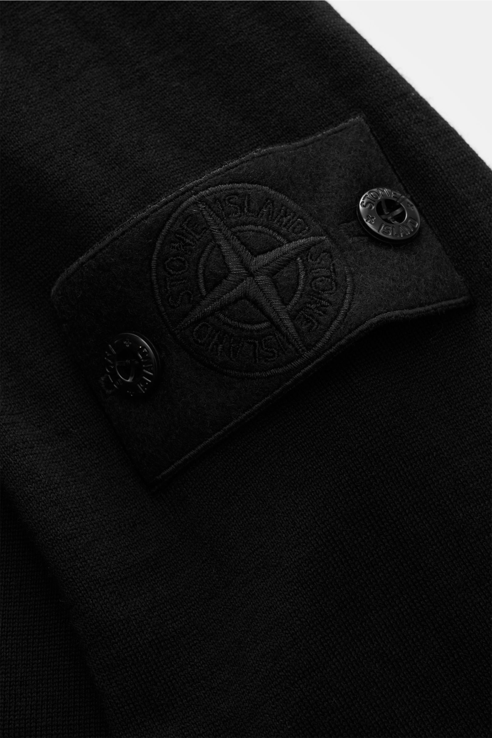 Nahaufnahme des schwarzen Stone Island Rundhalspullover 'Ghost Piece' mit tonalem Kompass-Badge am Oberarm aus feinem Wollstrick.