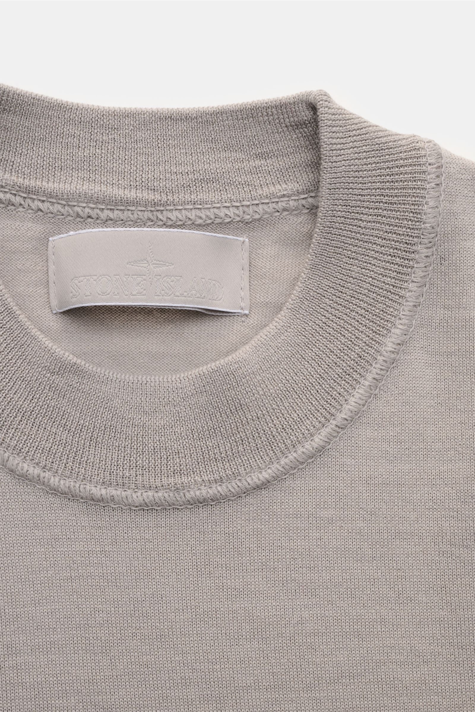 Stone Island Rundhalspullover 'Ghost Piece' grau, Nahaufnahme von oben, feines Strickbild, Rundhalsausschnitt, weiche Wolle, tonales Kompass-Badge.