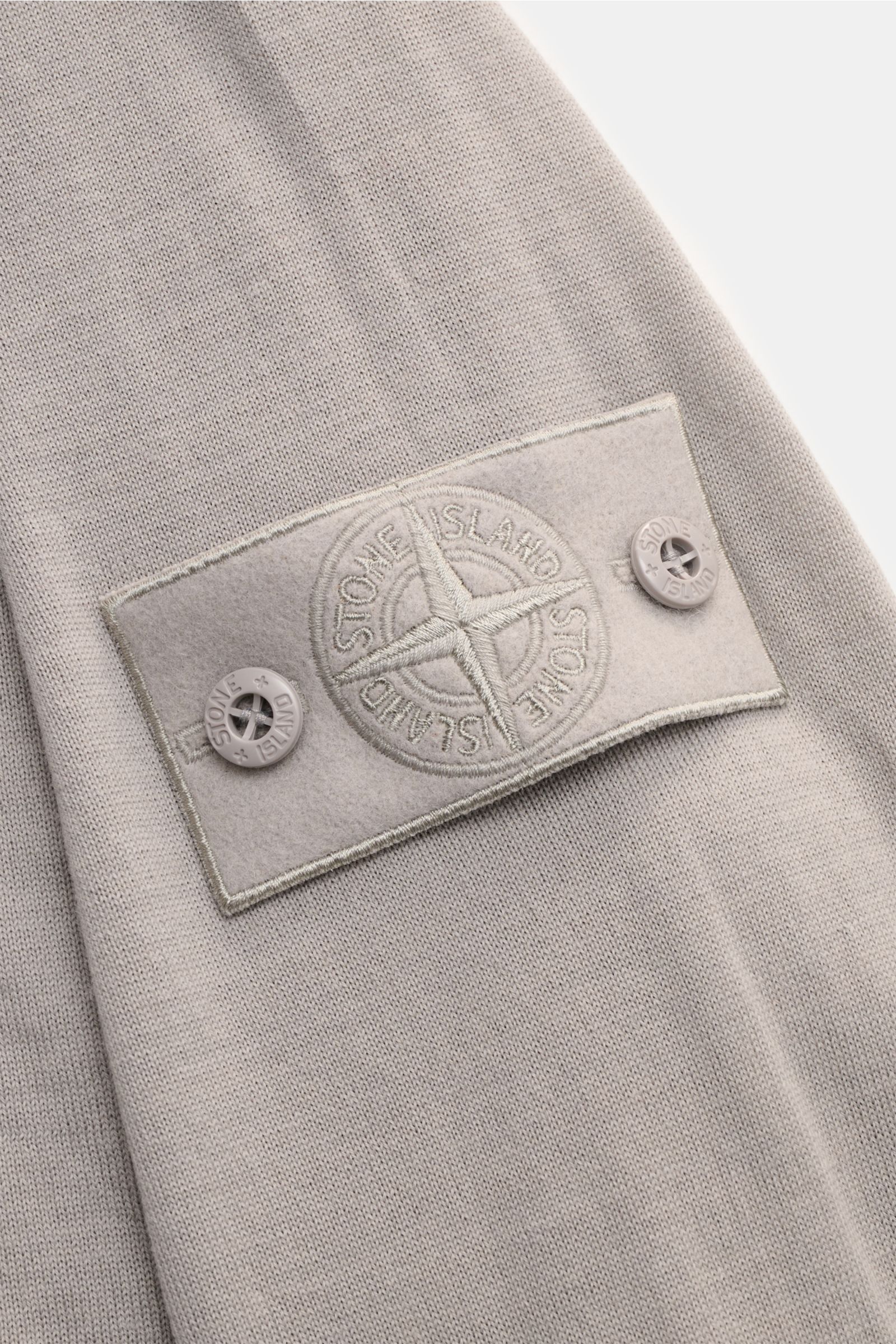 Stone Island Rundhalspullover 'Ghost Piece' grau, Detailaufnahme Ärmel mit tonalem Kompass-Badge, feine Wolle, weicher Griff, leichte Qualität.