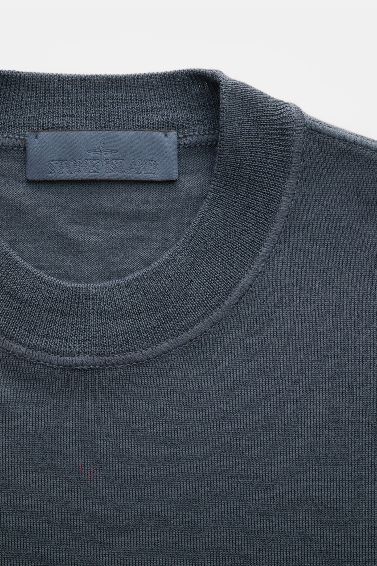 Stone Island Rundhalspullover 'Ghost Piece' dunkelgrau, feine Wolle, weicher Griff, Rundhalsausschnitt, tonales Kompass-Badge, Nahaufnahme von oben.