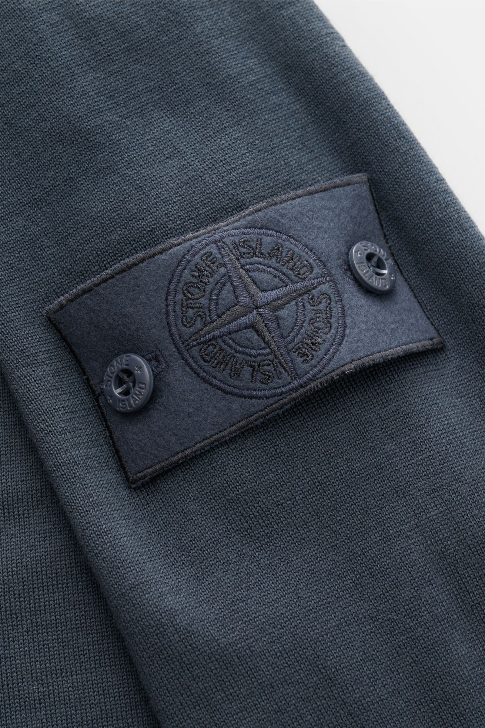 Stone Island Rundhalspullover 'Ghost Piece' dunkelgrau, Detailaufnahme von oben, feine Wolle, tonales Kompass-Badge am Ärmel, leichter Strick, Regular Fit.