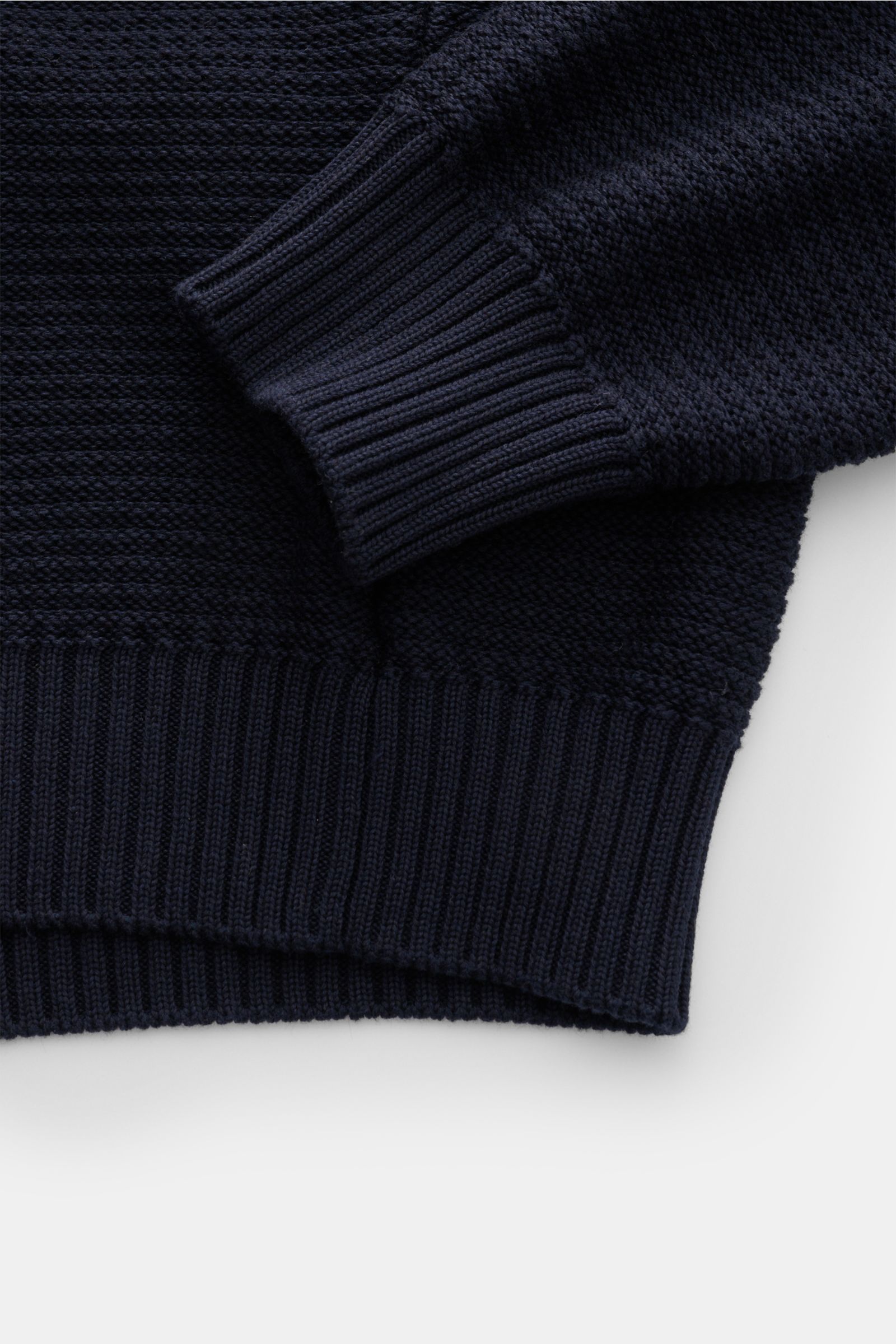 Nahaufnahme des Stone Island Rundhalspullover 'Ghost Piece' navy aus Baumwoll-Cashmere-Mix in linksgestrickter Rippe, mit elastischem Rippbündchen und tonalem Kompass-Badge, fotografiert von der Ärmel- und Bundperspektive.