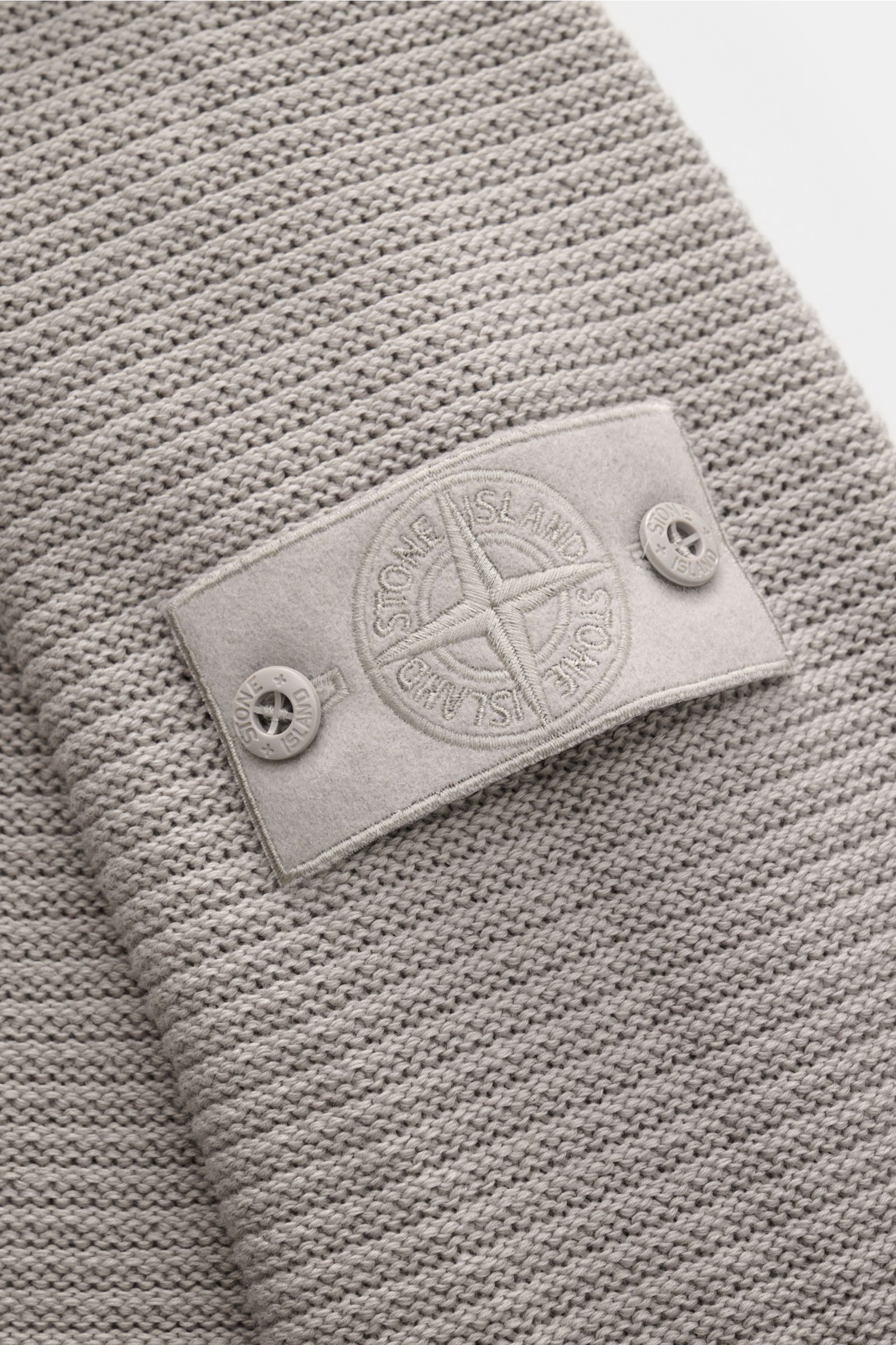 Stone Island Rundhalspullover 'Ghost Piece' grau, Nahaufnahme der linksgestrickten Rippe und tonales Kompass-Badge am Oberarm aus Baumwolle-Cashmere-Mix.