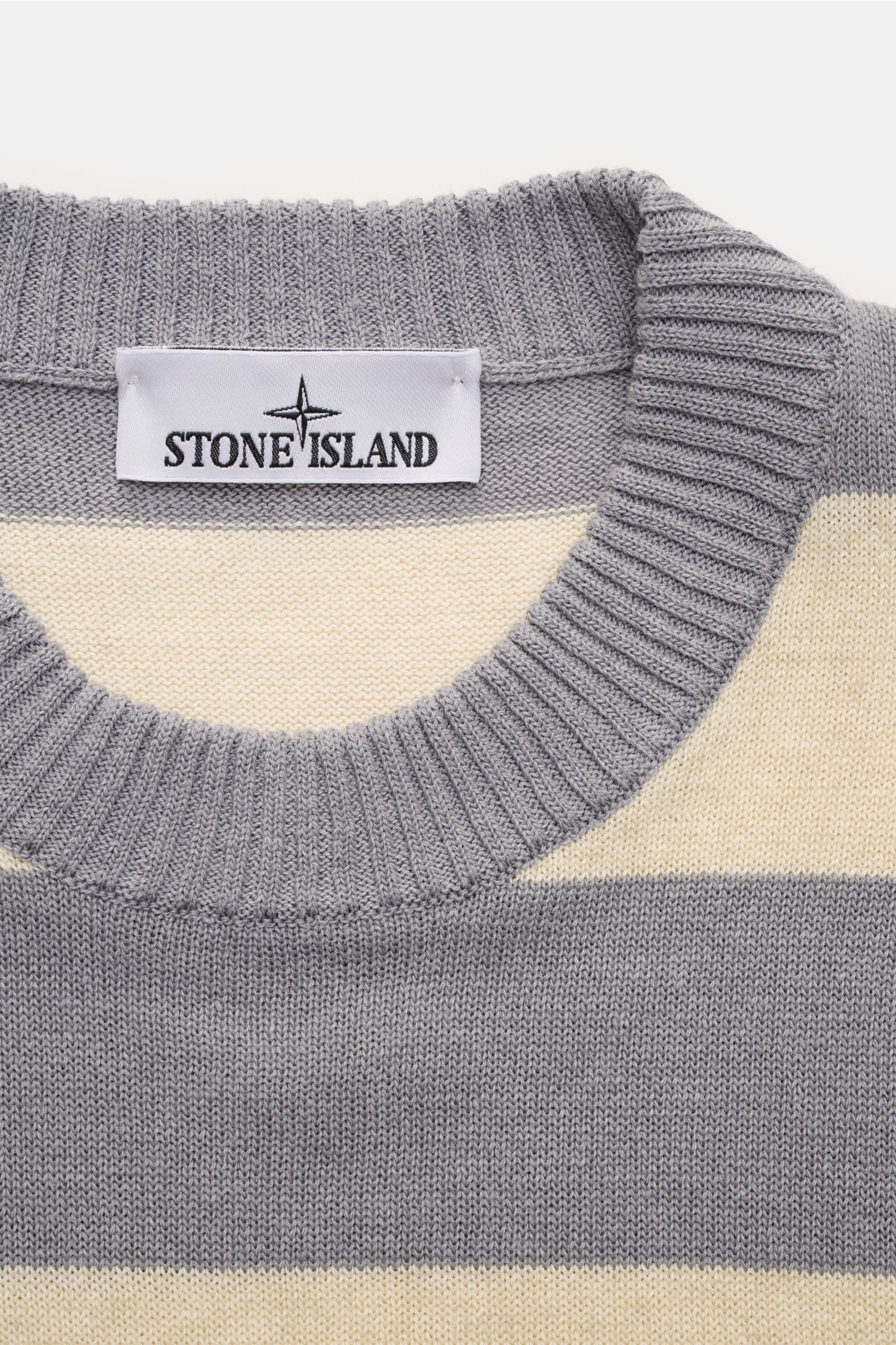 Stone Island Rundhalspullover 'Marina' grau/beige gestreift, Oversized Fit, Rundhalsausschnitt, mittelfeines Strickbild, leichte Baumwoll-Leinen-Mischung, Front mit MARINA-Print, Detailansicht vom Kragen und Label.