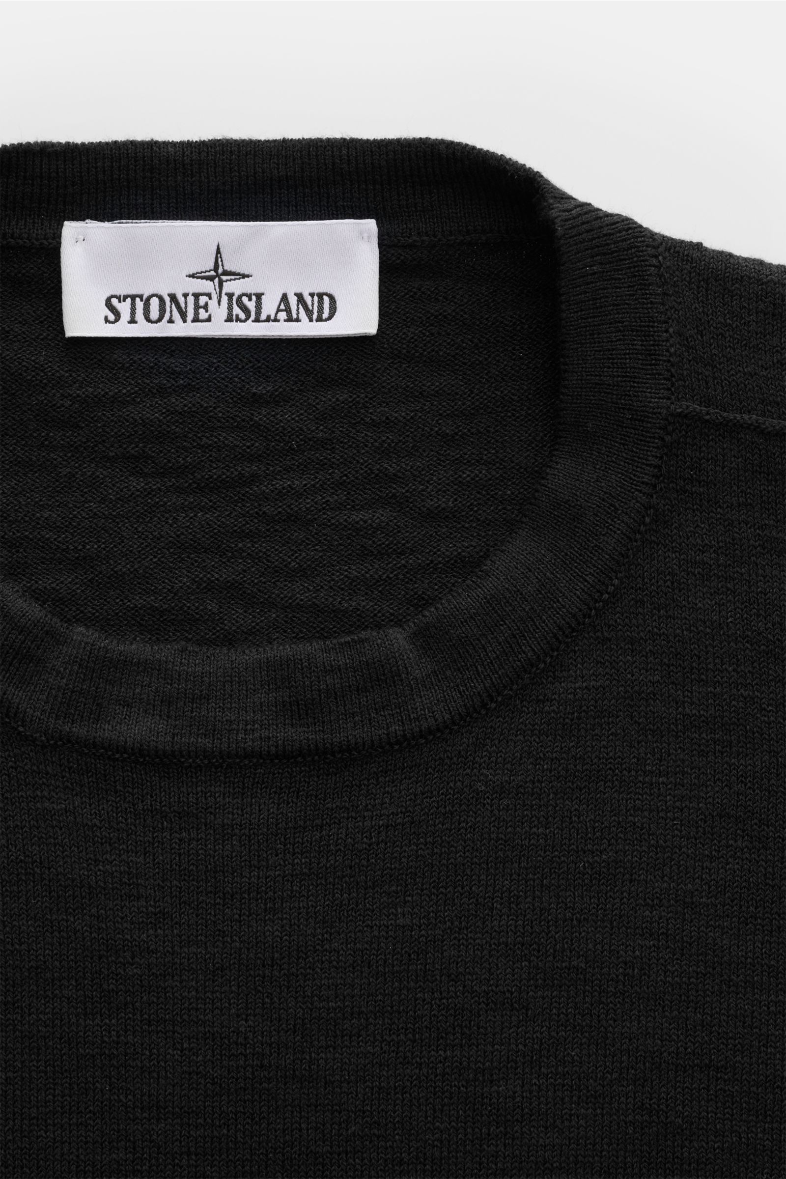 Stone Island Rundhalspullover schwarz, Slim Fit mit weichem Griff, feinem Strickbild, rundem Ausschnitt, rolliertem Saum, Kompass-Badge, frontal nah.