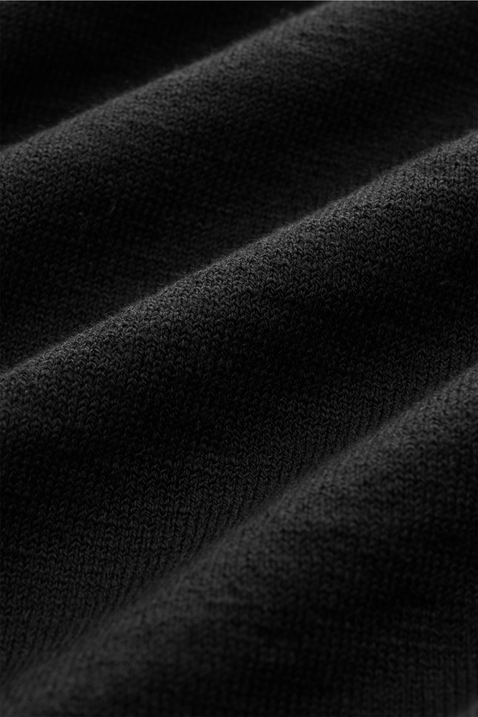 Stone Island Rundhalspullover schwarz im Detail, Nahaufnahme des feinen Strickbilds mit rollierten Saumkanten und Kompass-Badge, Slim Fit.