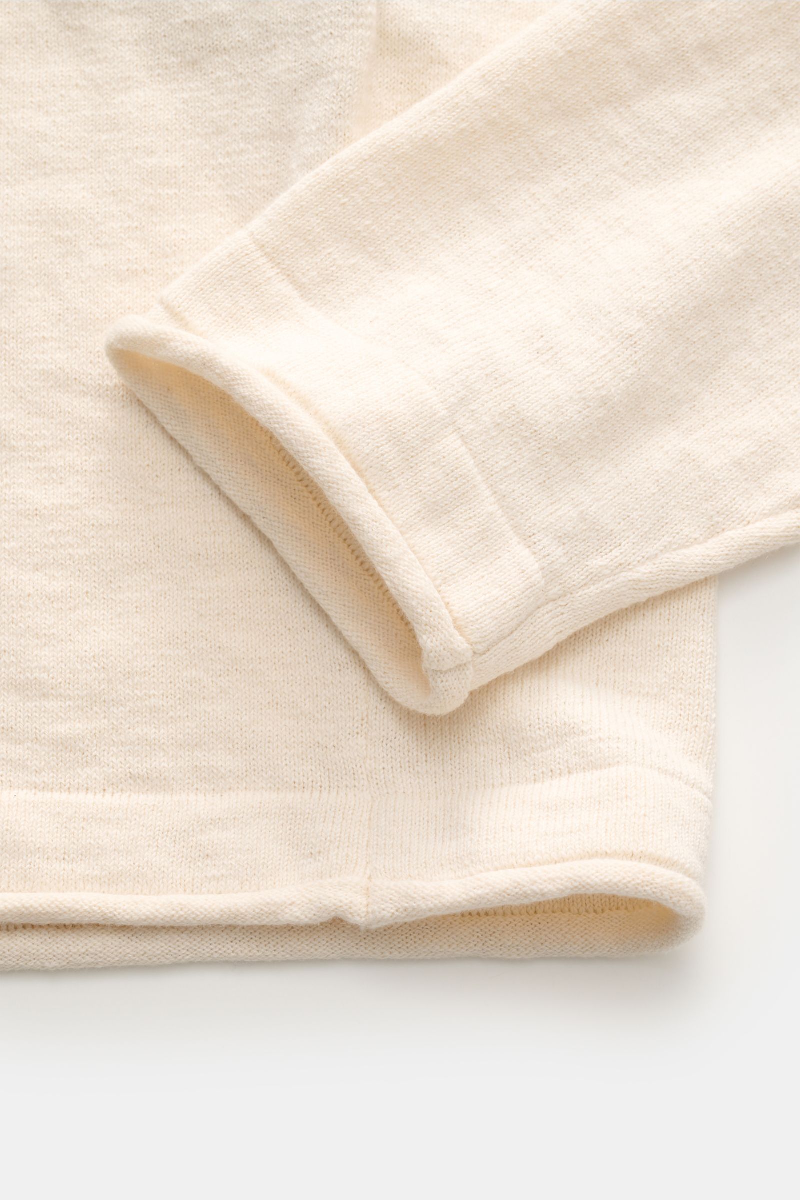 Nahaufnahme des Stone Island Rundhalspullover creme von schräg oben, zeigt feine Strickstruktur, rollierte Saumkanten und weichen Baumwoll-Microfaser-Mix.