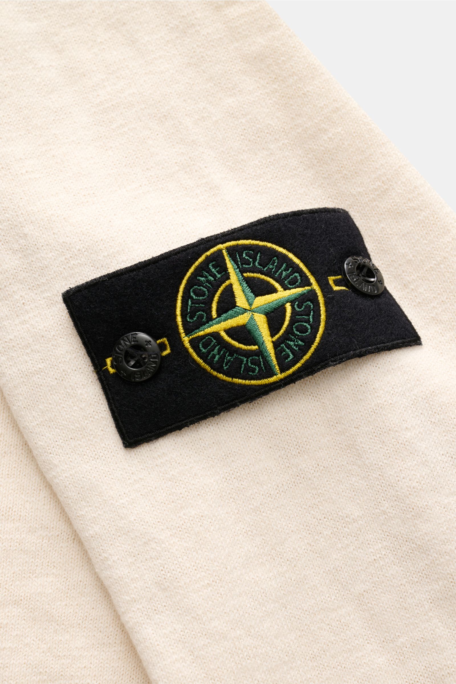 Stone Island Rundhalspullover creme in Slim Fit, weicher Baumwoll-Microfaser-Mix mit feinem Strickbild, Kompass-Badge und rolliertem Saum, Detailaufnahme seitlich.