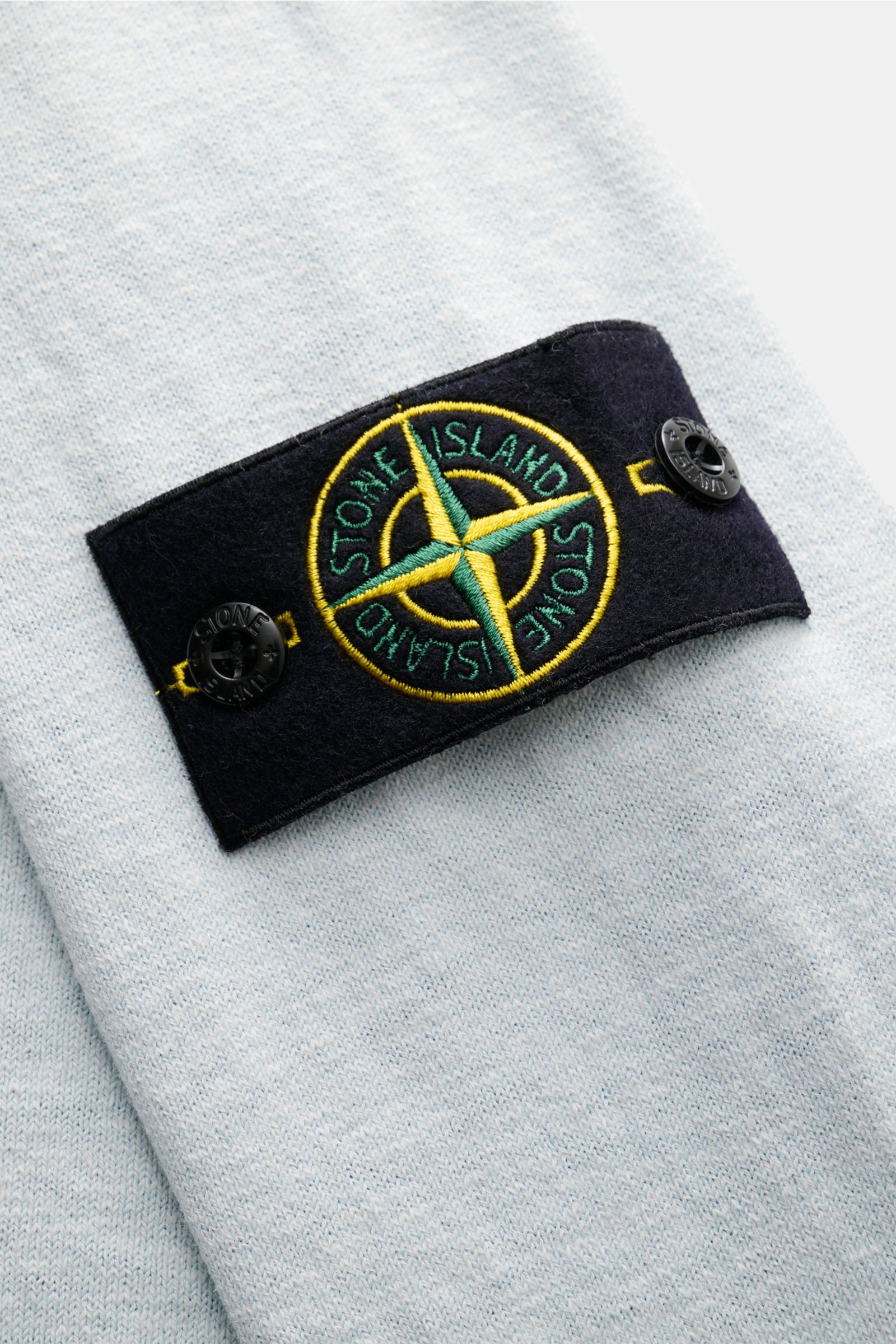 Stone Island Rundhalspullover pastellblau aus Baumwoll-Microfaser-Mix mit feinem Strickbild, rolliertem Saum, Slim Fit und typischem Kompass-Badge, Nahaufnahme.