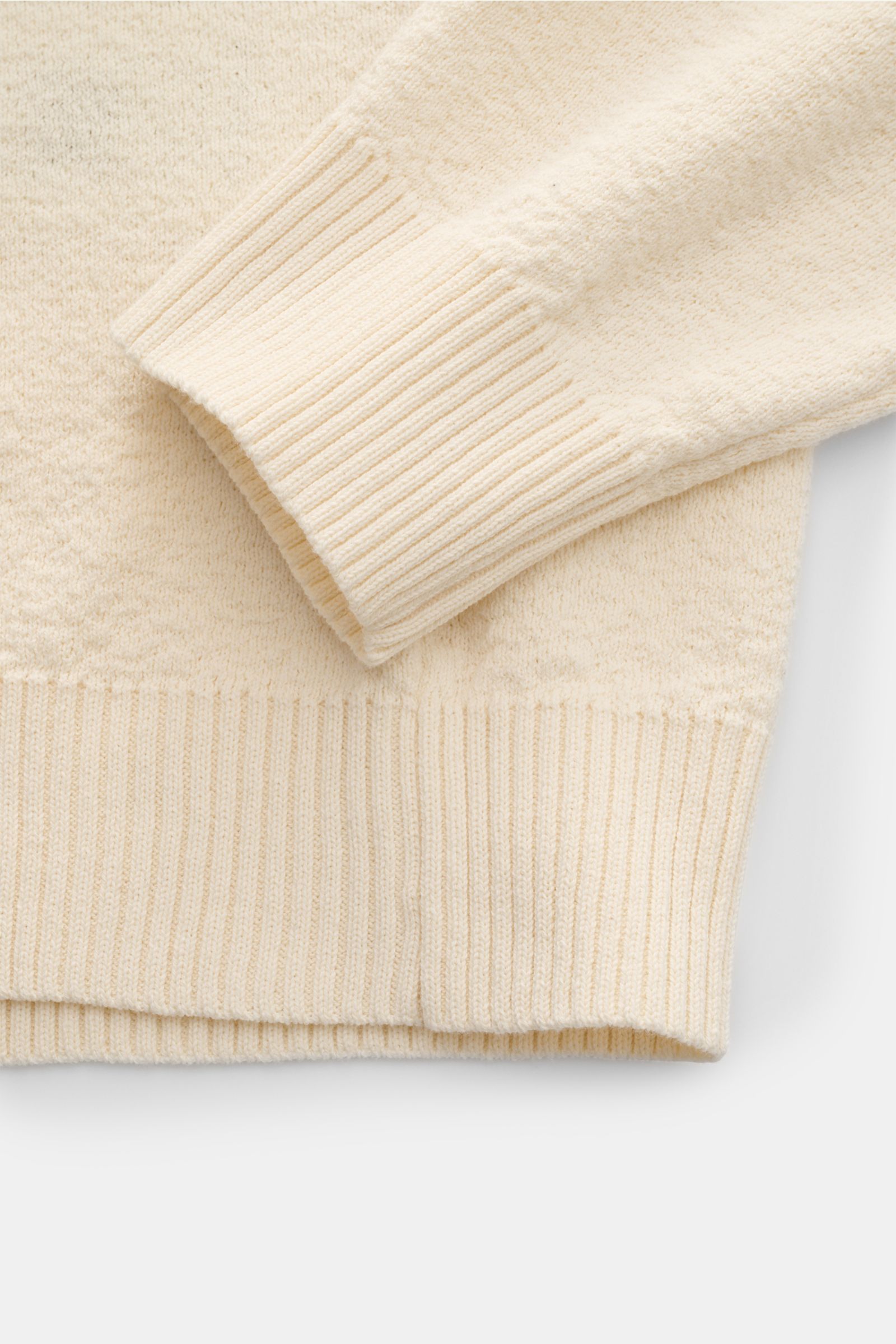 Stone Island Rundhalspullover creme aus leichtem Strick, Baumwolle mit crincle-Optik, Raglanärmel, Rippbündchen, Logo-Badge, Detailaufnahme von Ärmel und Saum.