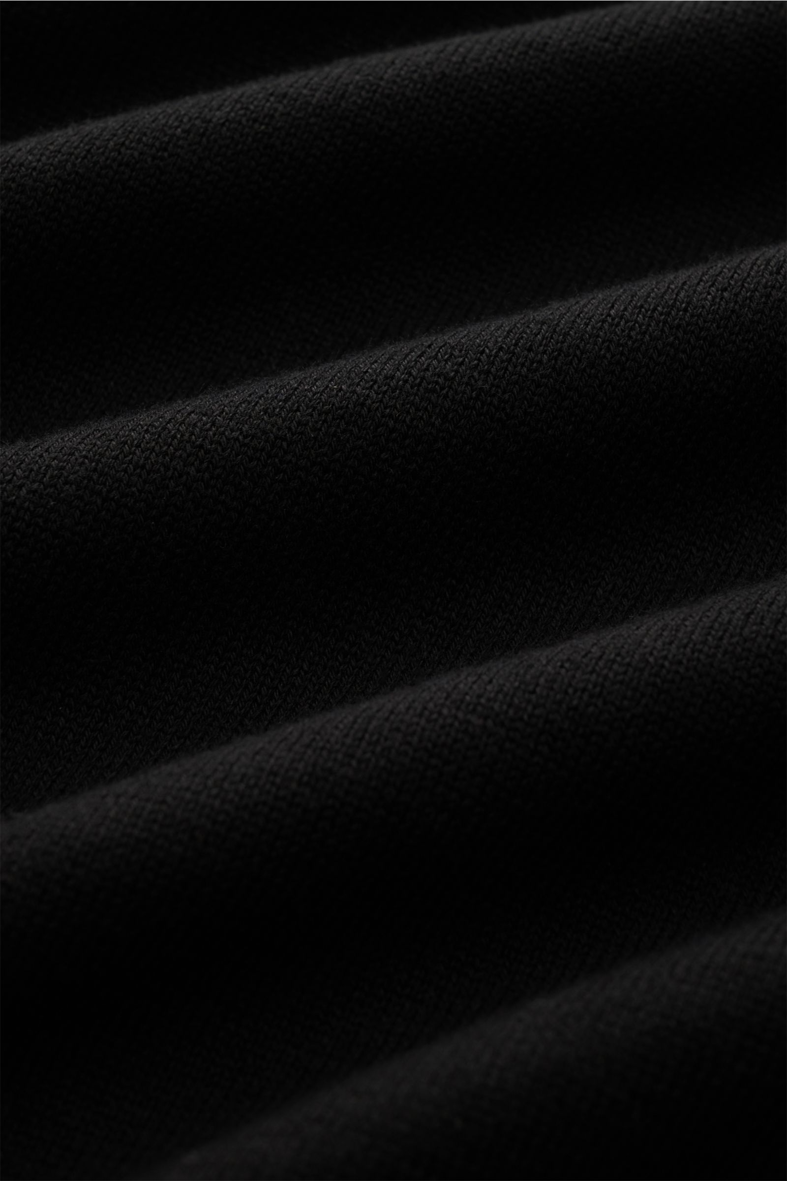 Nahaufnahme des schwarzen Stone Island Rundhalspullover aus feinem, weichem Baumwollstrick mit sichtbarer Struktur und Komfort.