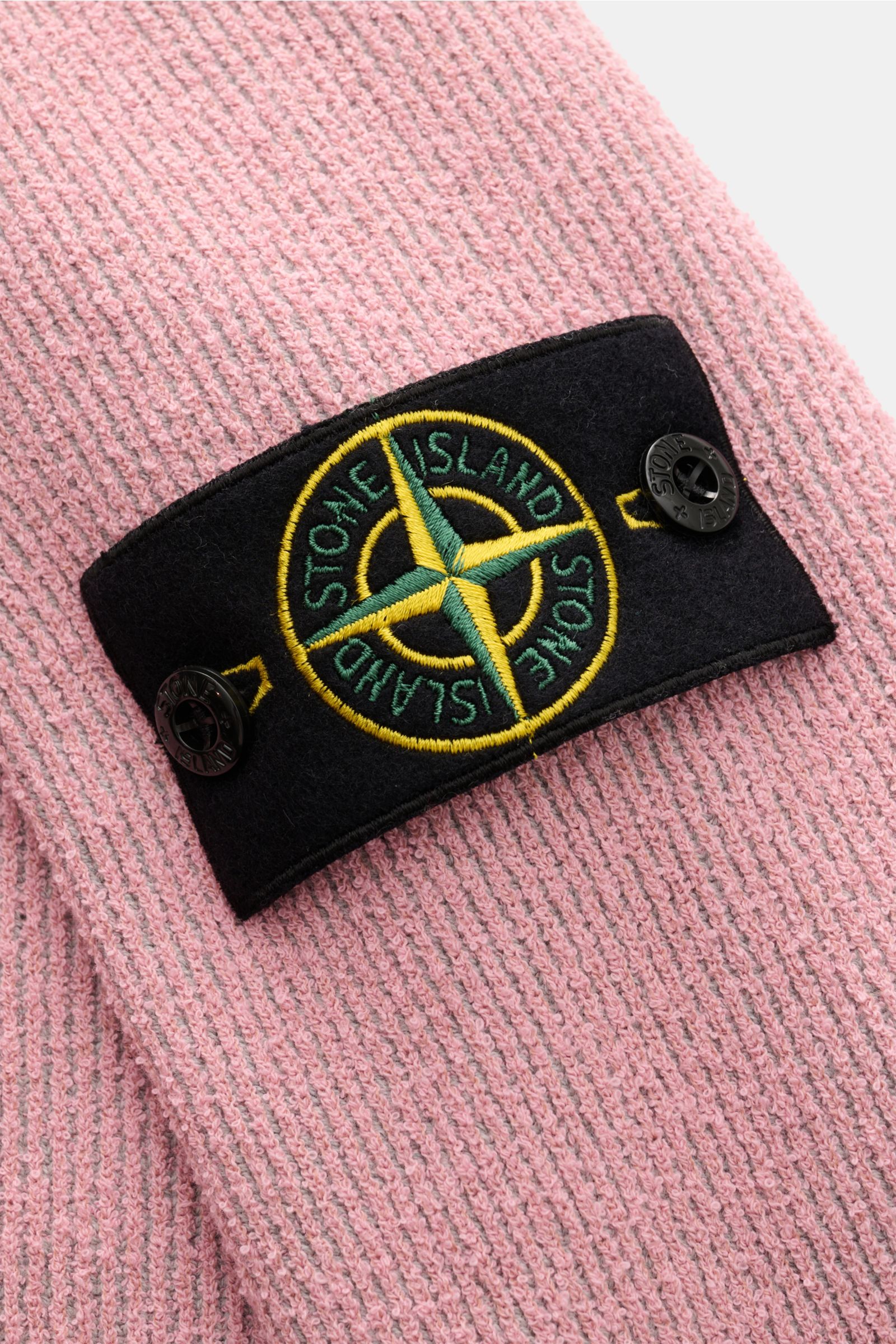 Nahaufnahme des Stone Island Rundhalspullover rosé in Rippstrick aus kernigem Loop-Garn mit Kompass-Badge am Oberarm.