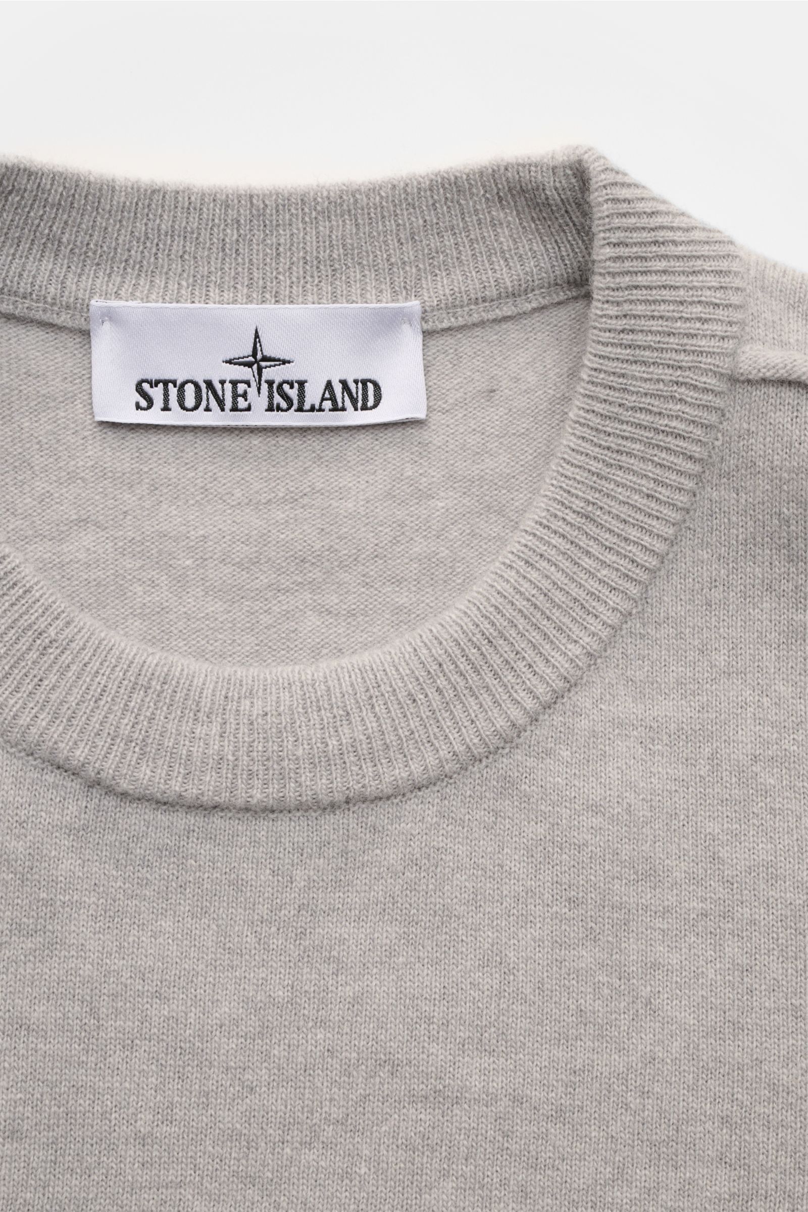 Close-up top-down view of Stone Island Crew neck jumper grey showing fine knit, elasticated ribbed crew neck, and white label with black logo.

Description: 
A timeless piece from STONE ISLAND: If you want to create a warm, sporty look, you can’t go wr