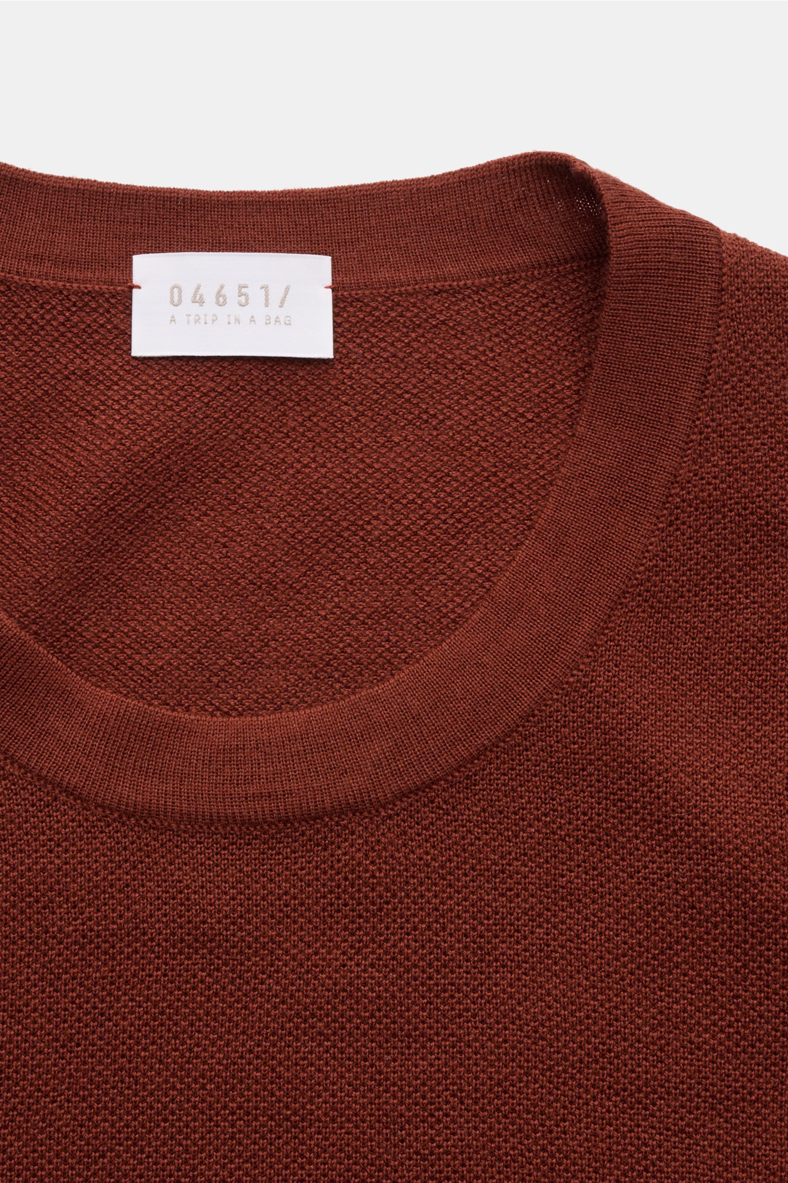 Close-up top-down view of the neckline and fabric texture of the 04651/ A trip in a bag Feinstrick-Rundhalspullover dunkelblau meliert. Zeitloser Klassiker für die Herbst- und Wintersaison: Der Rundhalspullover von 04651/ A TRIP IN A BAG lässt sich vielse