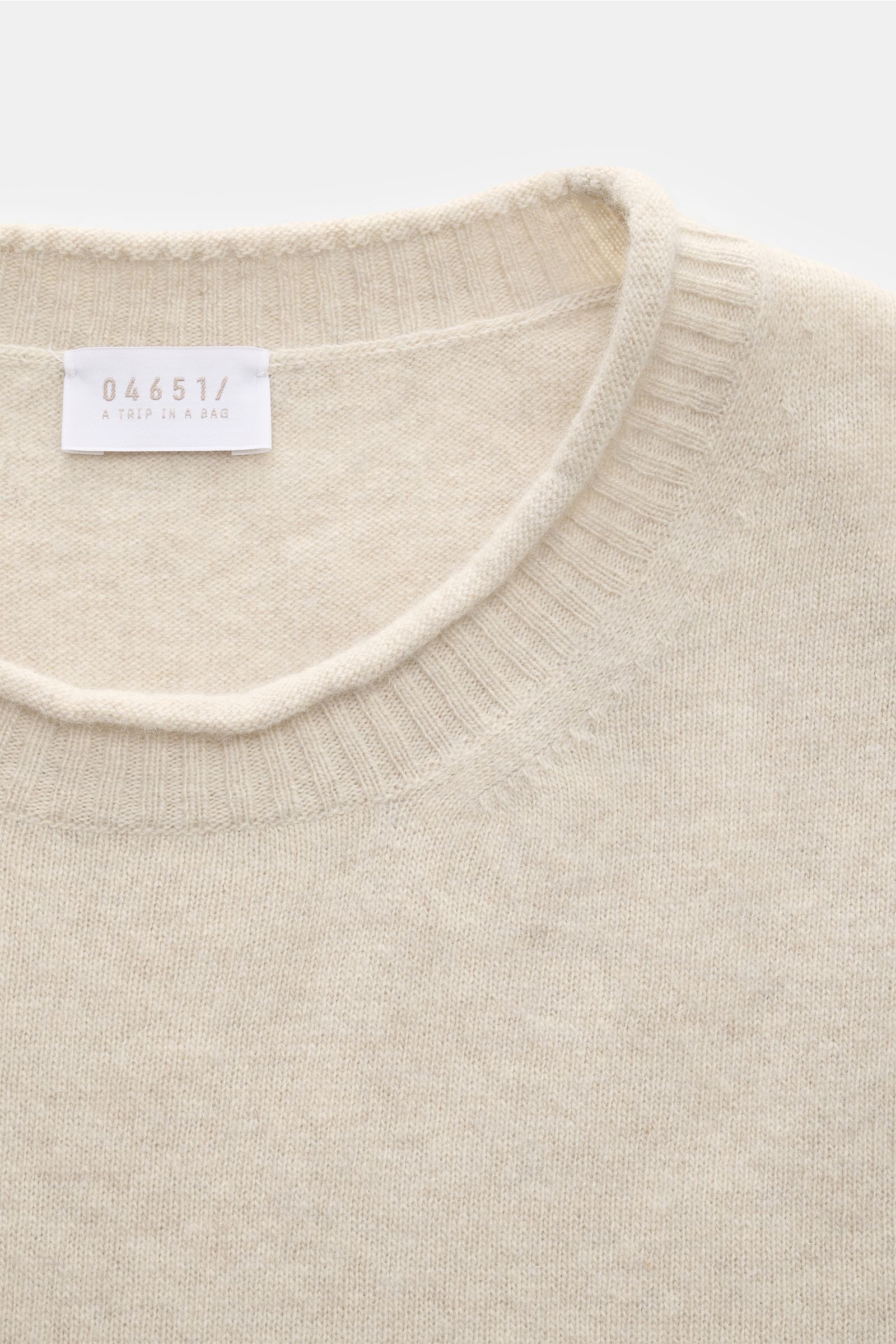 Close-up top-down view of the sand-colored 04651/ A trip in a bag Crew neck jumper 'Boiled Crew' showing the fine knit fabric and ribbed crew neck. Stylish comfort for cold days: This crew neck jumper by 04651/ A TRIP IN A BAG is a versatile piece with ti