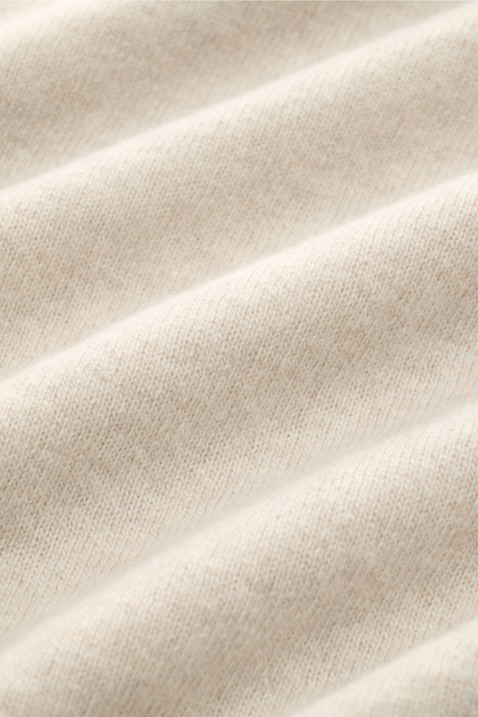 Close-up view of soft, fine knit fabric in sand color showcasing texture and ribbed details of the 04651/ A trip in a bag Crew neck jumper 'Boiled Crew' sand. Stylish comfort for cold days: This crew neck jumper by 04651/ A TRIP IN A BAG is a versatile pi