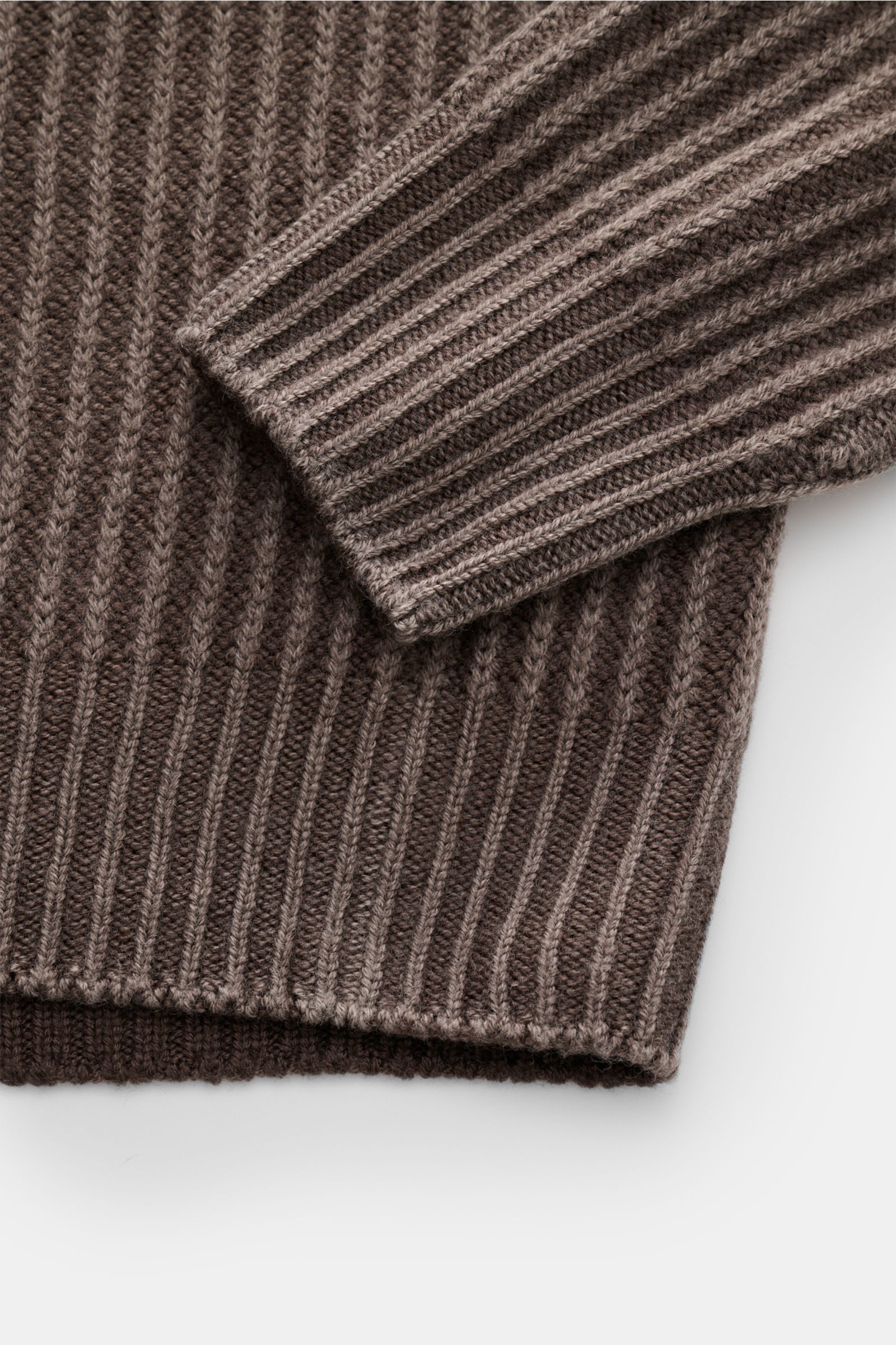 Close-up, top-down view of the sleeve and hem of the 04651/ A trip in a bag Mock Neck Pullover 'Foggy Mock' taupe, showing a garment dyed, slim fit, pure wool pullover with soft touch, medium-fine knit, coarse ribbed pattern, mock neck, and comfortable ri