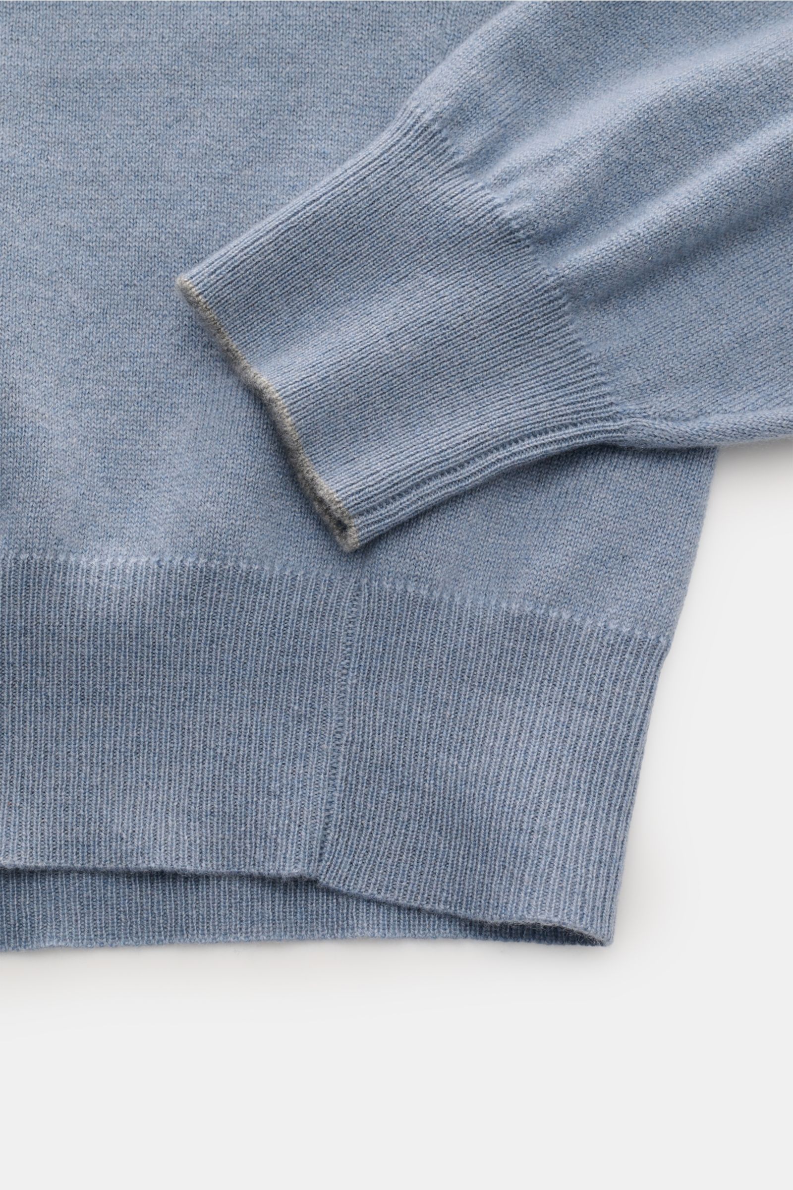 Brunello Cucinelli Cashmere Rundhalspullover rauchblau shown from a close-up side angle, highlighting fine knit, soft texture, and ribbed cuffs. Als vielseitiges Essential bietet dieser luxuriöse Cashmerepullover mit Rundhalsausschnitt von BRUNELLO CUC