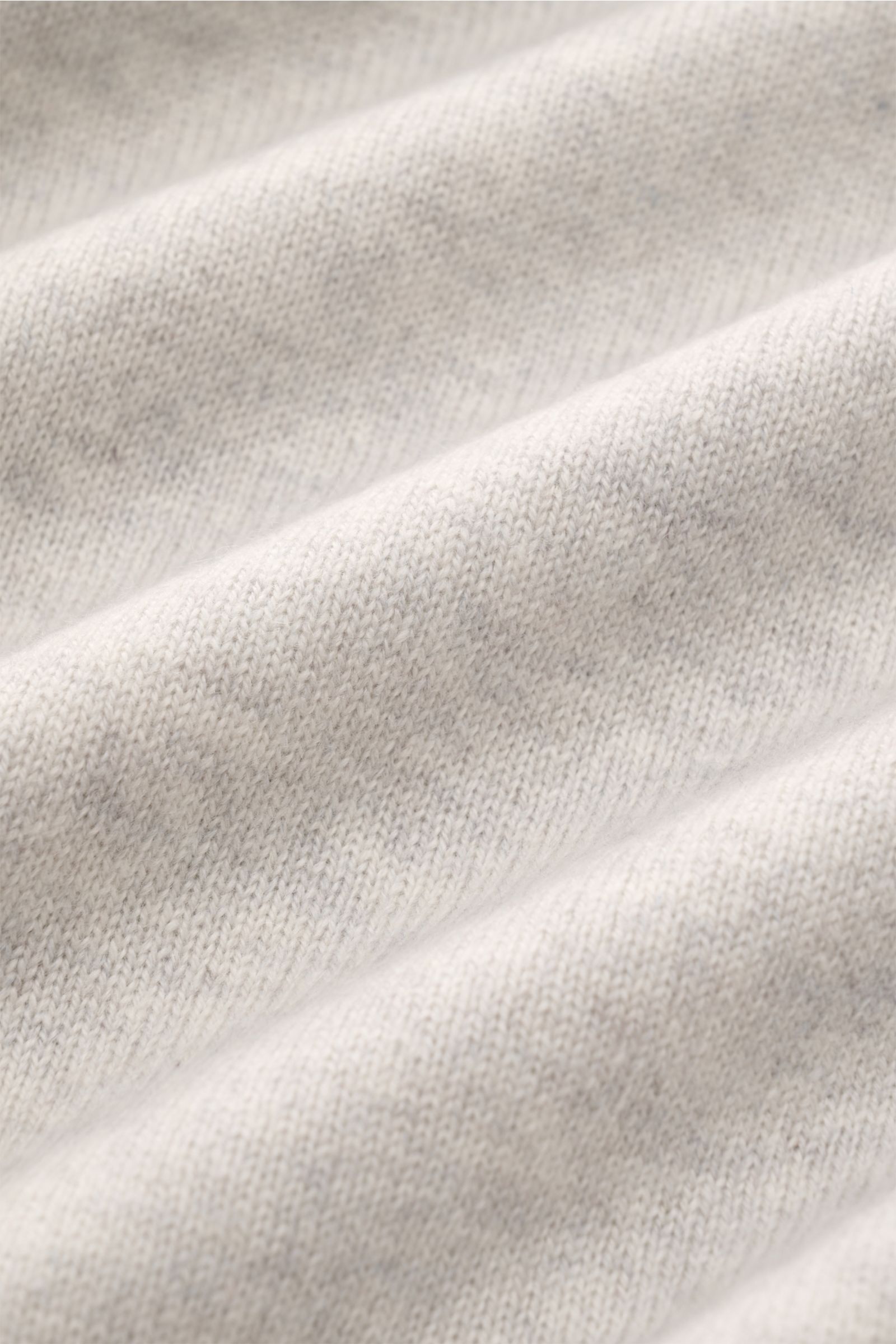 Close-up front view of the finely knitted light grey melange fabric of the Brunello Cucinelli Cashmere V-Neck Pullover hellgrau meliert, showcasing its pure cashmere texture and very soft feel. Luxuriöser Cashmere in Verbindung mit klassischem Design: Der